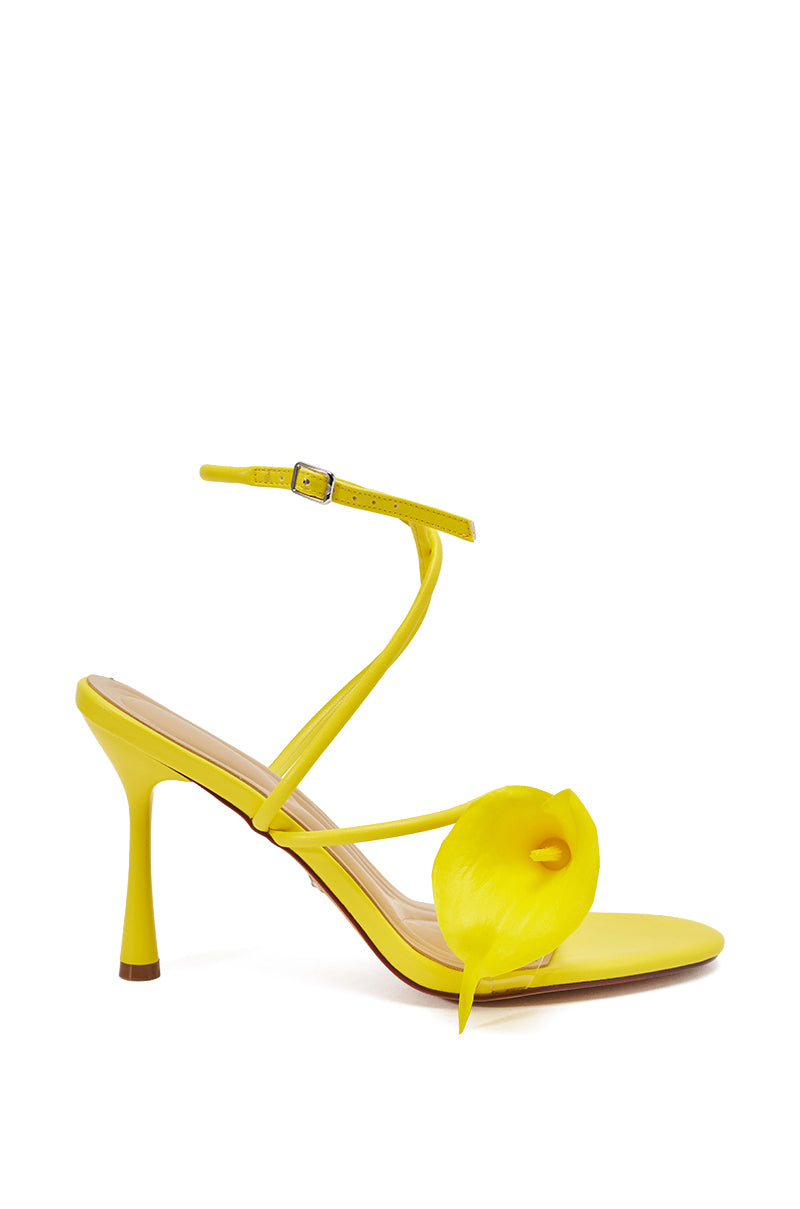 The AZALEA WANG NILOU YELLOW FLORAL DECALE STRAP STILETTO SANDAL features a yellow ankle strap, slender stiletto heel, and a decorative calla lily flower on the front strap, shown against a white background. 5