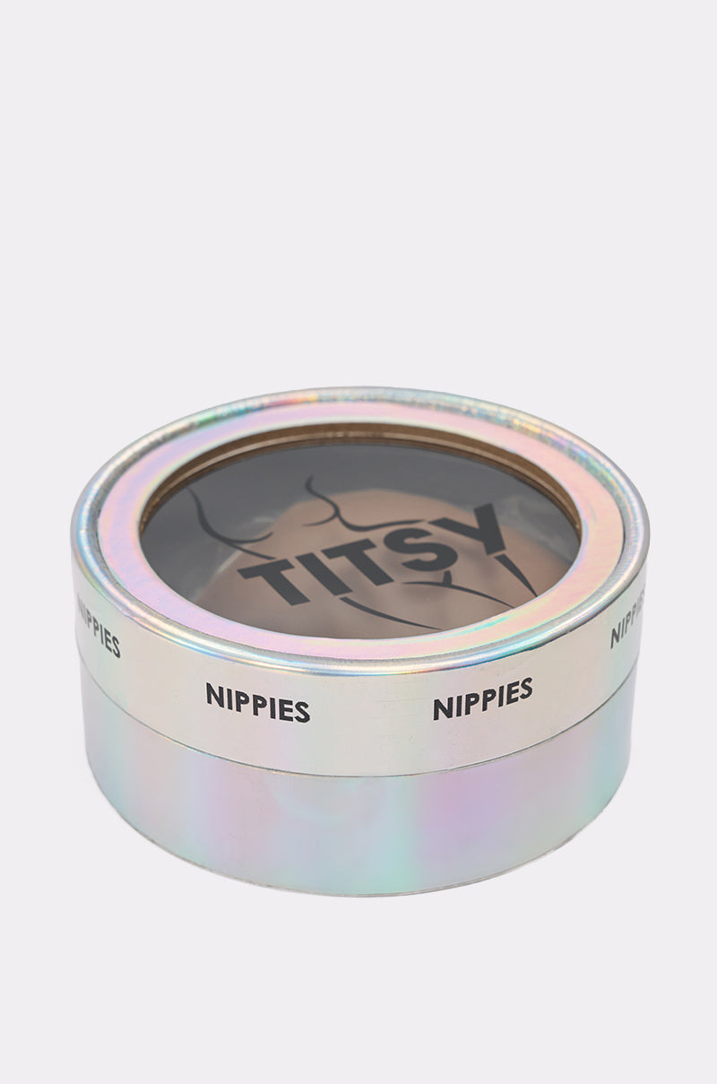 Round, iridescent box labeled "TITSY ADHESIVE SILICONE NIPPIE PETAL" with a clear lid showing adhesive nipple covers inside—ideal for seamless coverage or as dark silicone nipple covers. 2