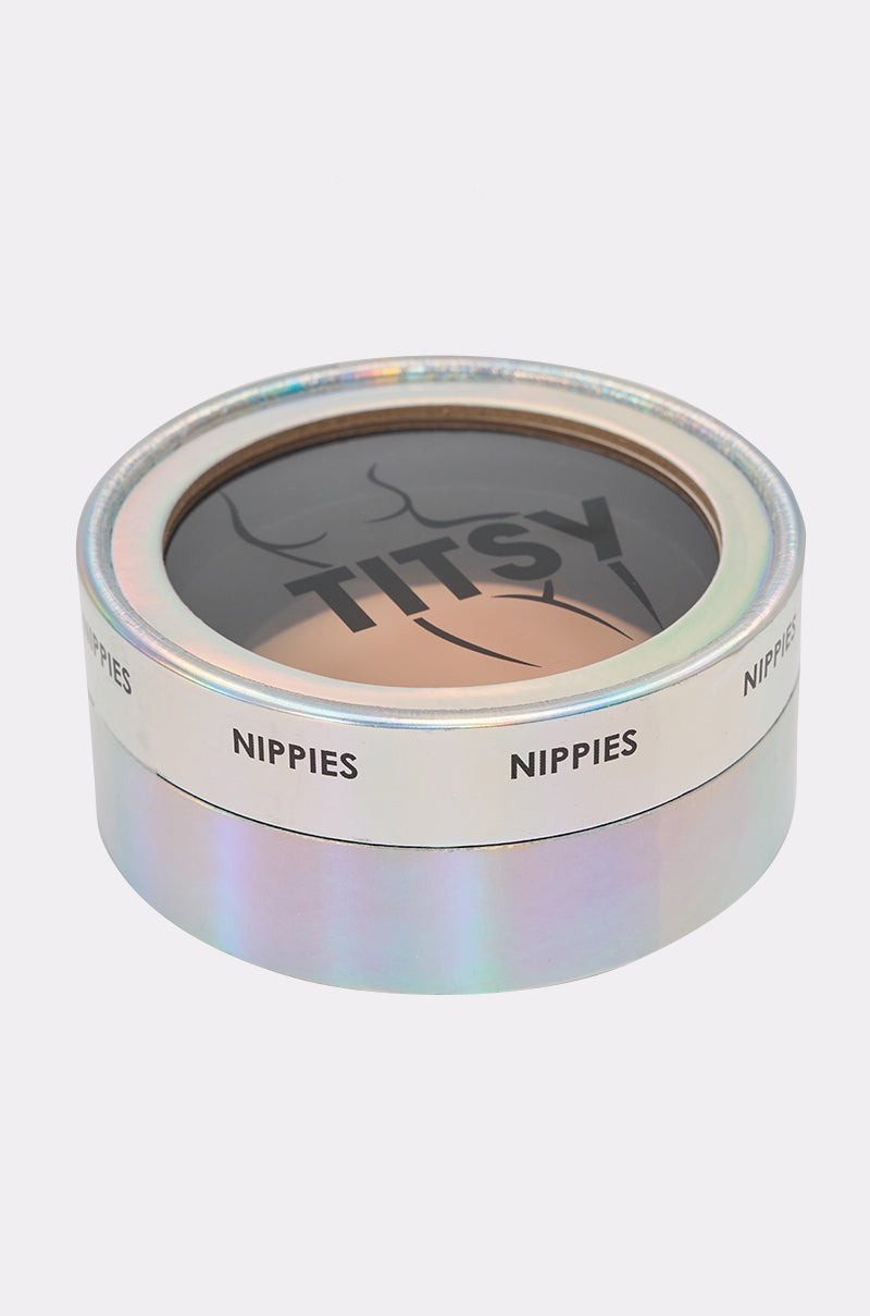 A round, iridescent box labeled "NIPPIES" around the side has a clear lid displaying TITSY ADHESIVE SILICONE NIPPIE PETAL inside, with "TITSY" printed on the top insert. 2