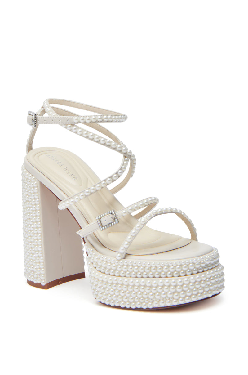 The AZALEA WANG NIYA IVORY PEARL SANDAL features multiple thin white faux leather straps with small pearls, a chunky pearl-covered heel, and a silver ankle buckle for an elegant, stylish look.
