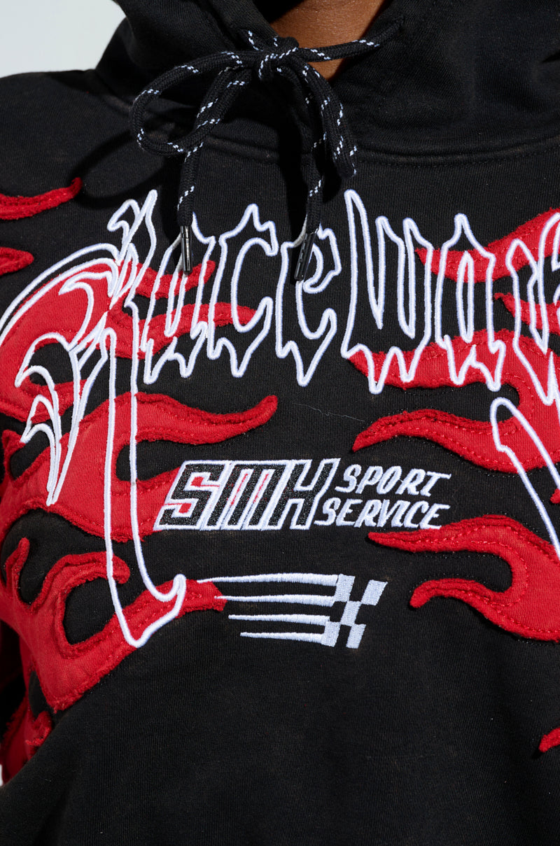 Close-up of a black ON FIRE SWEATSHIRT featuring embroidered flame designs and bold text "Raceway." Smaller text reads "SMK Sport Service," accompanied by a racing flag, perfectly capturing the sweatshirt’s racing-inspired style.