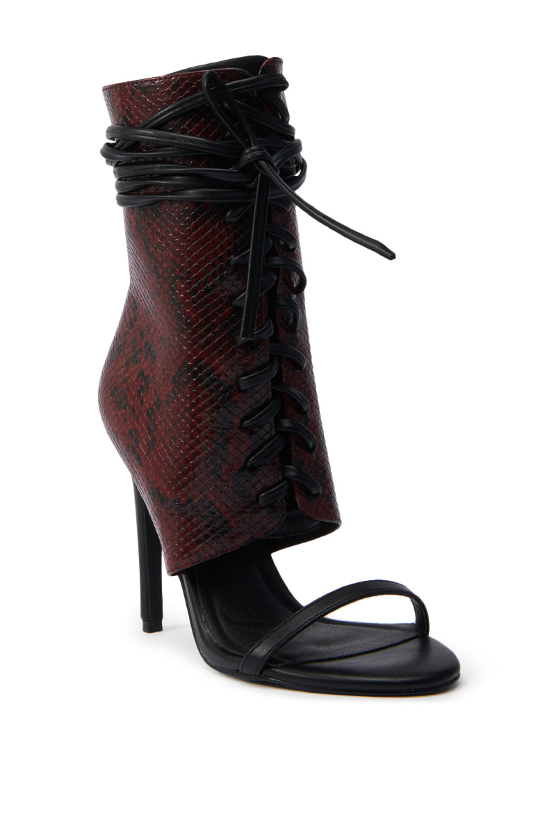 The AZALEA WANG NOLYN BURGUNDY SNAKE OPEN TOE BOOTIE features a high heel, red and black faux snakeskin upper, lace-up front, open toe, black ankle wrap laces, and a thin black strap across the toes. 2