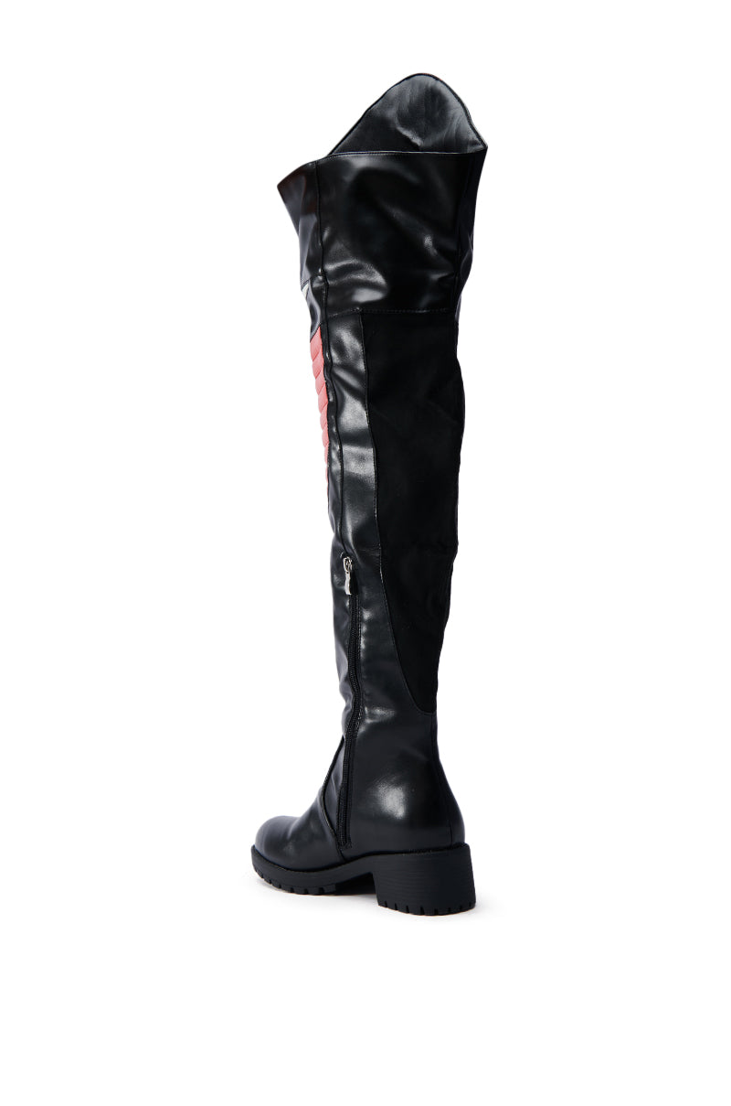 A NORRIS RED AND BLACK FLAT BOOT, featuring faux leather with glossy and matte textures, knee-high design, side zipper, and thick rubber lug sole, stands upright against a plain white background.