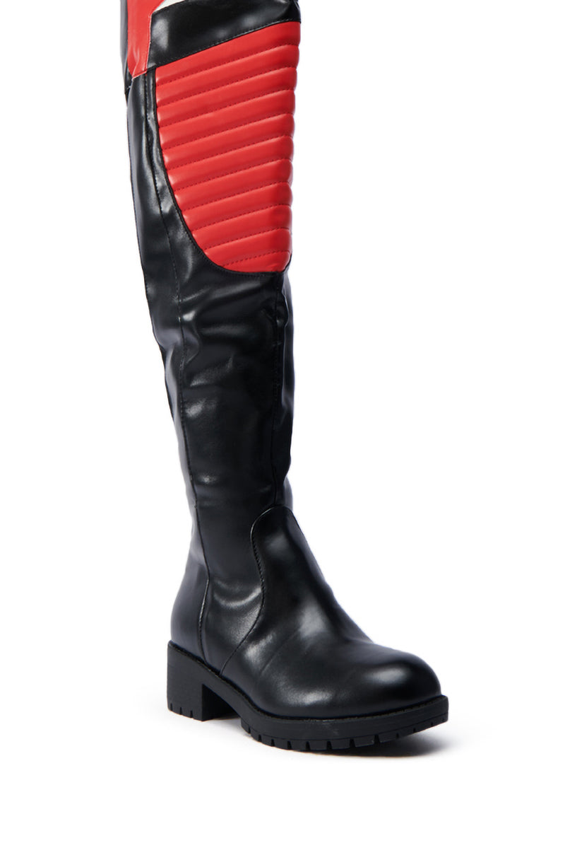 The NORRIS RED AND BLACK FLAT BOOT is a knee-high, black faux leather boot with a chunky rubber lug sole and a bold red quilted panel on the upper front.