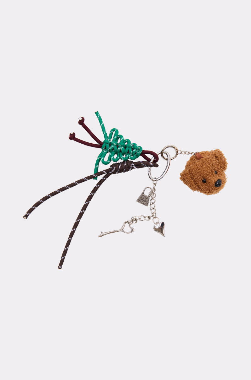The ULTIMATE KEYCHAIN SET includes a fuzzy brown teddy bear head, green and brown cords, and silver charms (heart, triangle, tiny key) for a playful maximalist touch to your keychain collection.