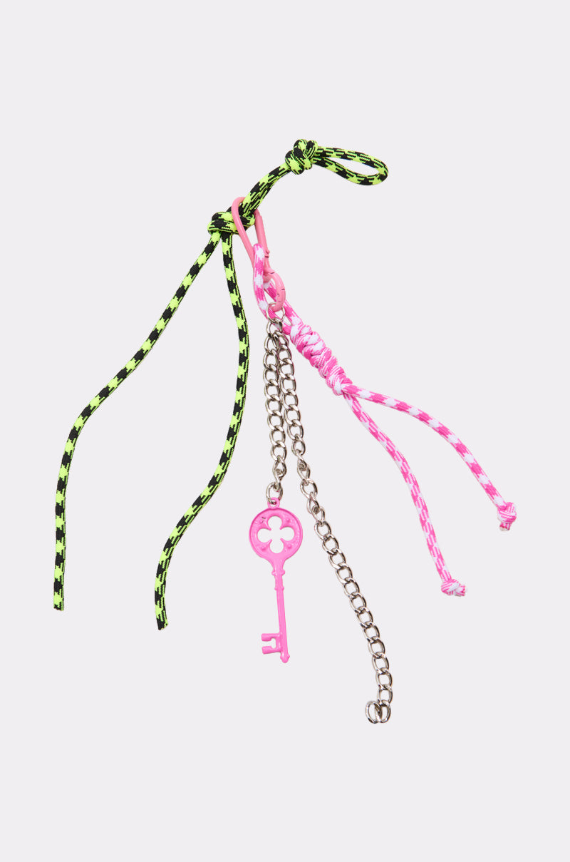 The ULTIMATE KEYCHAIN SET is a maximalist accessory featuring green and black braided cords, pink and white braided cords, a silver chain, and a pink key-shaped charm with a clover design at the top.