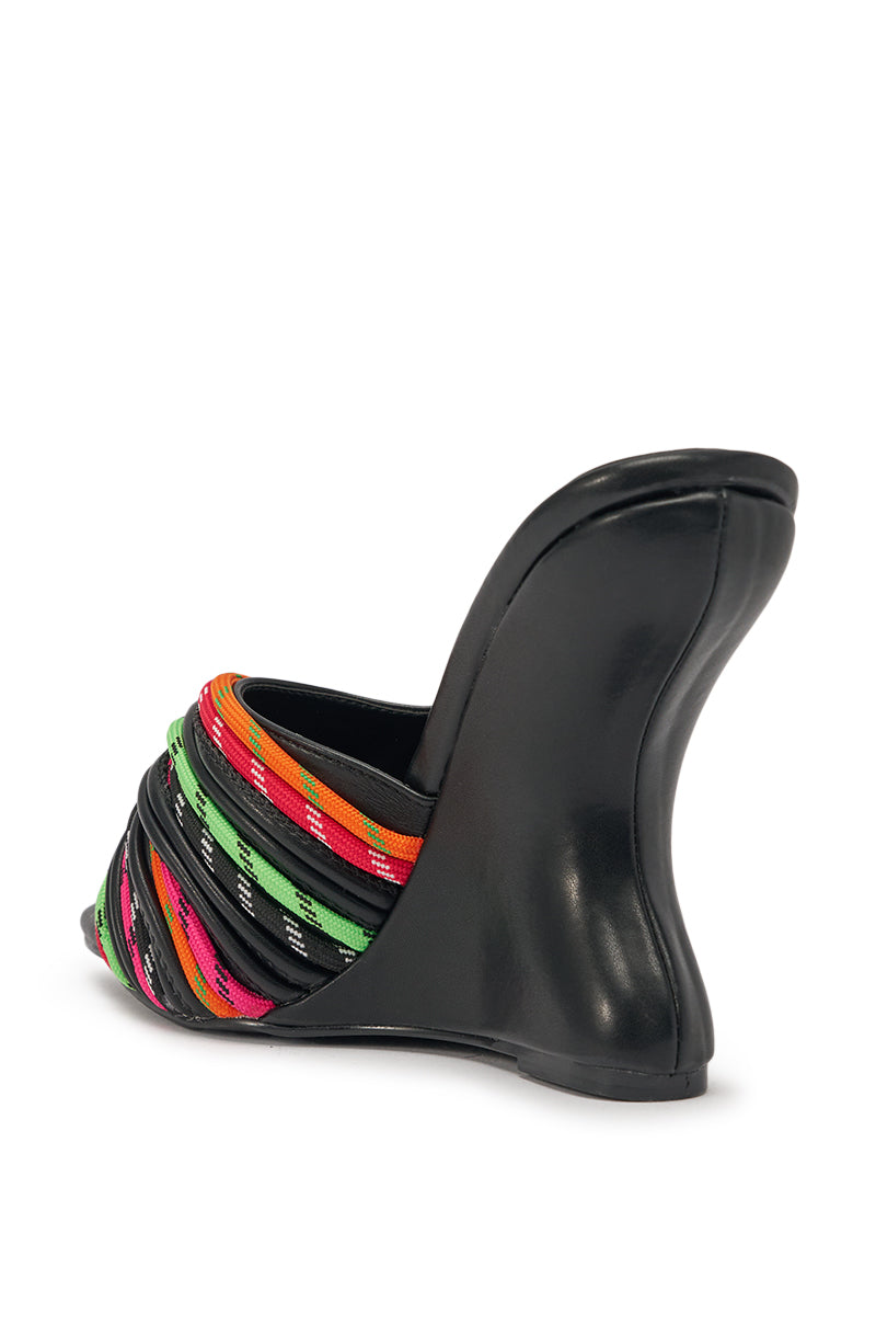 The AKIRA GOLD NOWITZKI MULTI WEDGE AND SHOE LACE SANDAL features a black faux leather sculptural wedge heel and multicolor braided straps—green, orange, pink, yellow, and black—wrapping over the front. Shown from the back side. 5