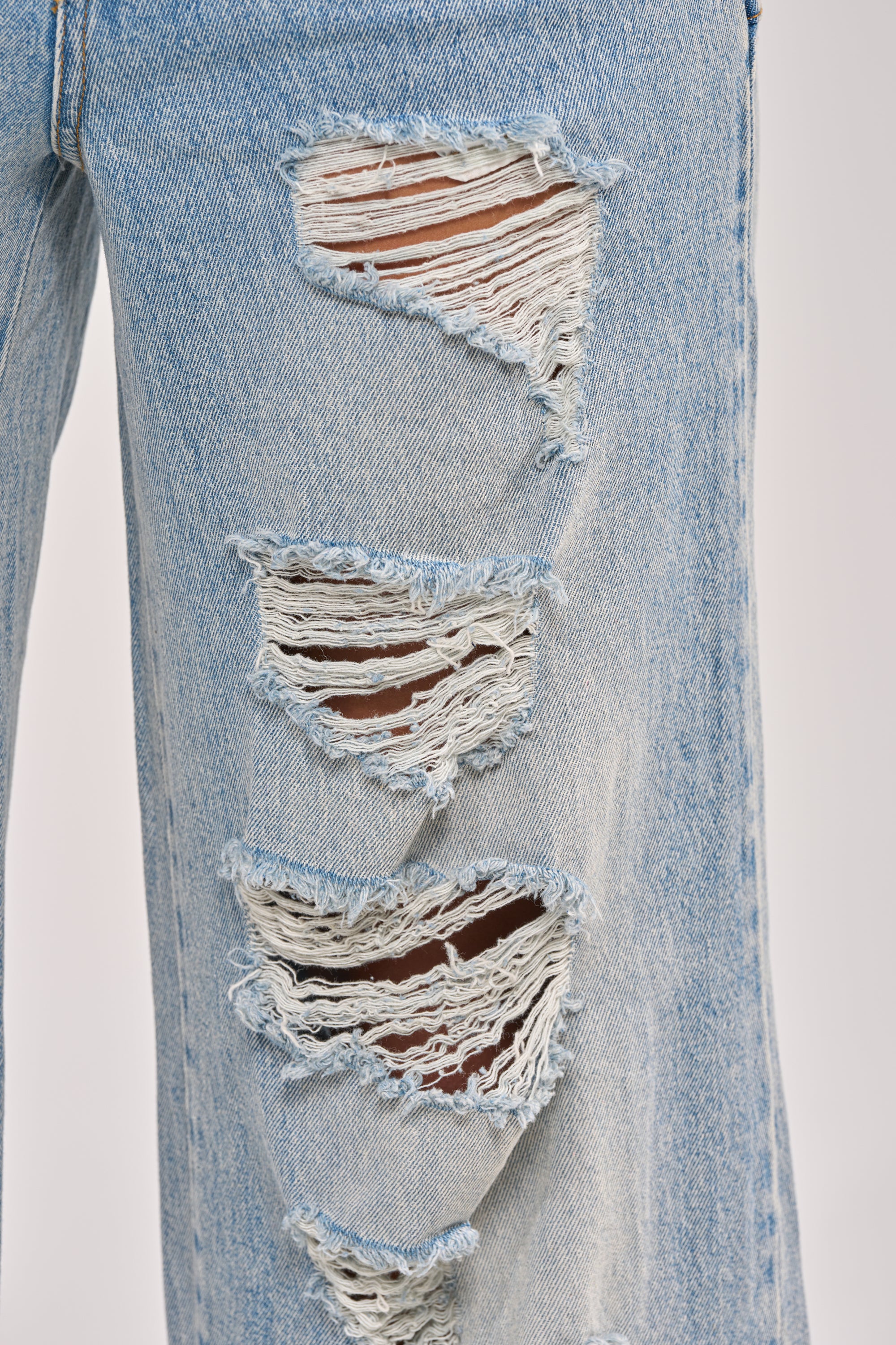 A close-up of the GO GET SOME DOUBLE WAISTED DENIM, featuring distressed high-rise wide-leg jeans with multiple large horizontal rips and frayed edges on the upper thigh and knee. 8