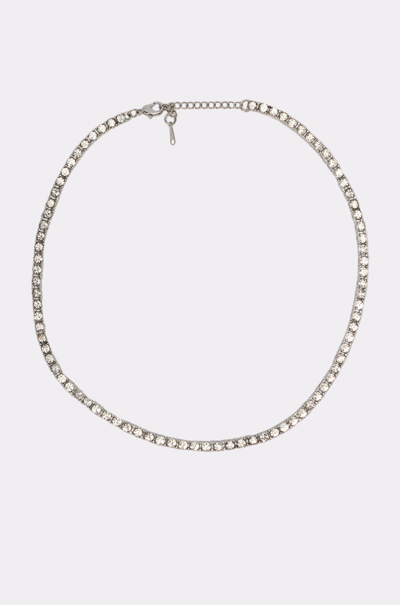 The WHAT U SAY NECKLACE is a delicate silver choker featuring a row of round rhinestones and an adjustable clasp, adding sparkle and elegance to layered looks. Shown against a plain white background. 3