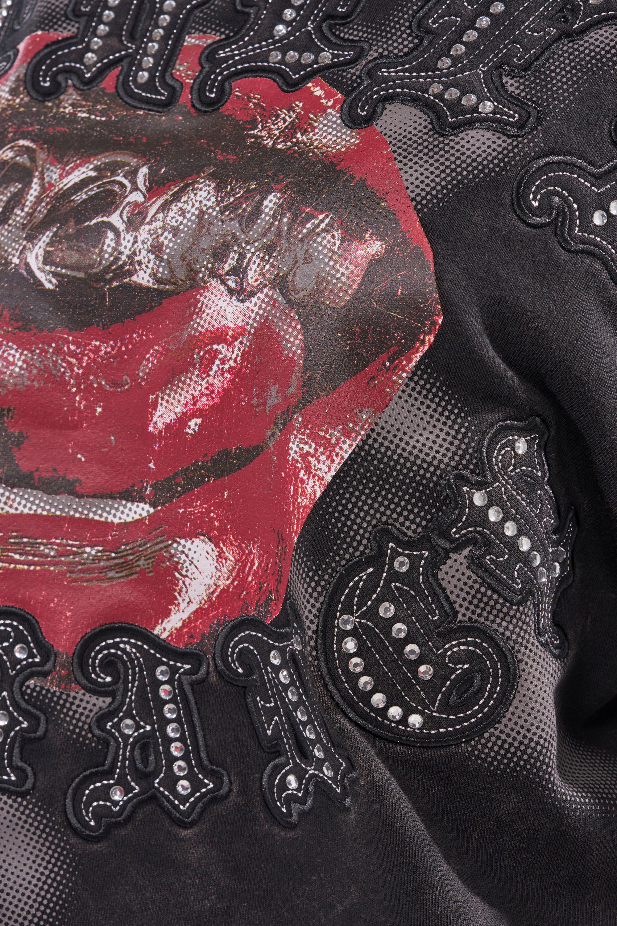 Close-up of the STREET ELEGANCE GRAPHIC TEE—a black shirt with a textured design of red lips and studded, gothic-style lettering for a standout streetwear look. 10