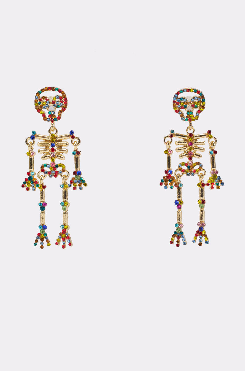 The SKELLY EARRINGS are a pair of gold skeleton dangle earrings adorned with colorful gemstones, displayed against a plain white background. These statement earrings are perfect for adding a bold touch to any look.
