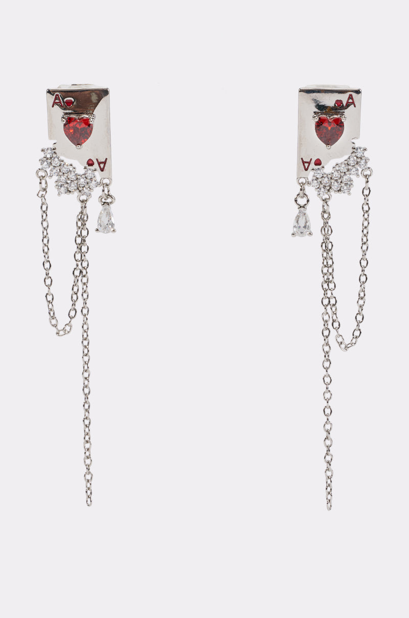PLAY UR CARDS RIGHT EARRINGS are silver statement drop earrings shaped like ace of hearts playing cards, featuring sparkling red heart gems, small clear stones, and hanging silver chains.