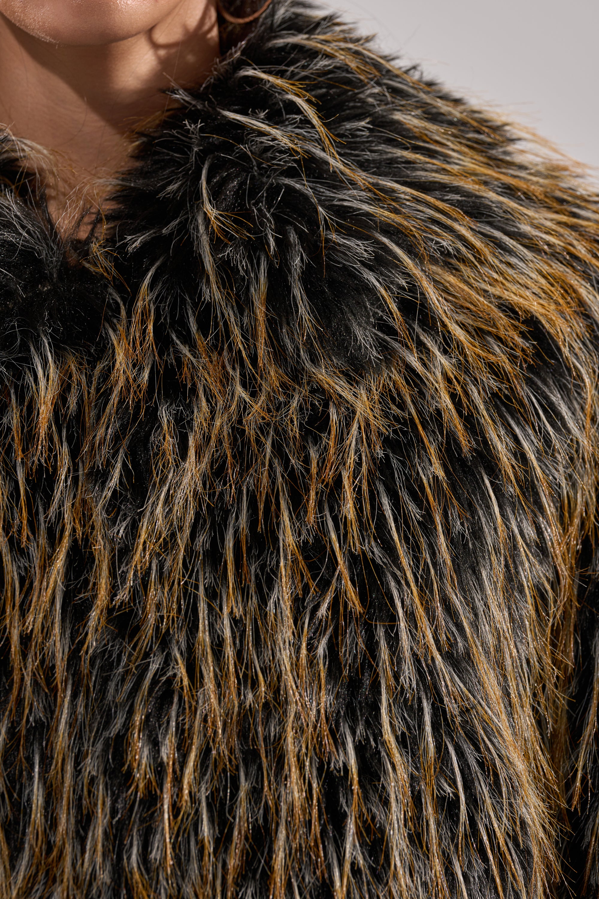 Close-up of a person in the JUPITER FAUX FUR COAT featuring thick, long textured faux fur and an oversized collar. Only the lower face and neck are shown, making this cozy winter jacket the focal point.