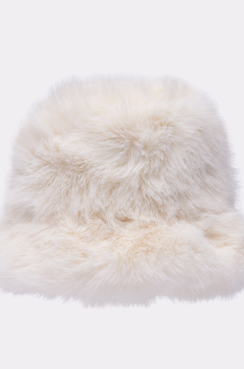 The BABY IT'S COLD OUTSIDE FAUX FUR BUCKET HAT IN IVORY is displayed against a plain, light background. Its soft, plush faux fur and wide brim make it a cozy and stylish accessory for winter looks. 6