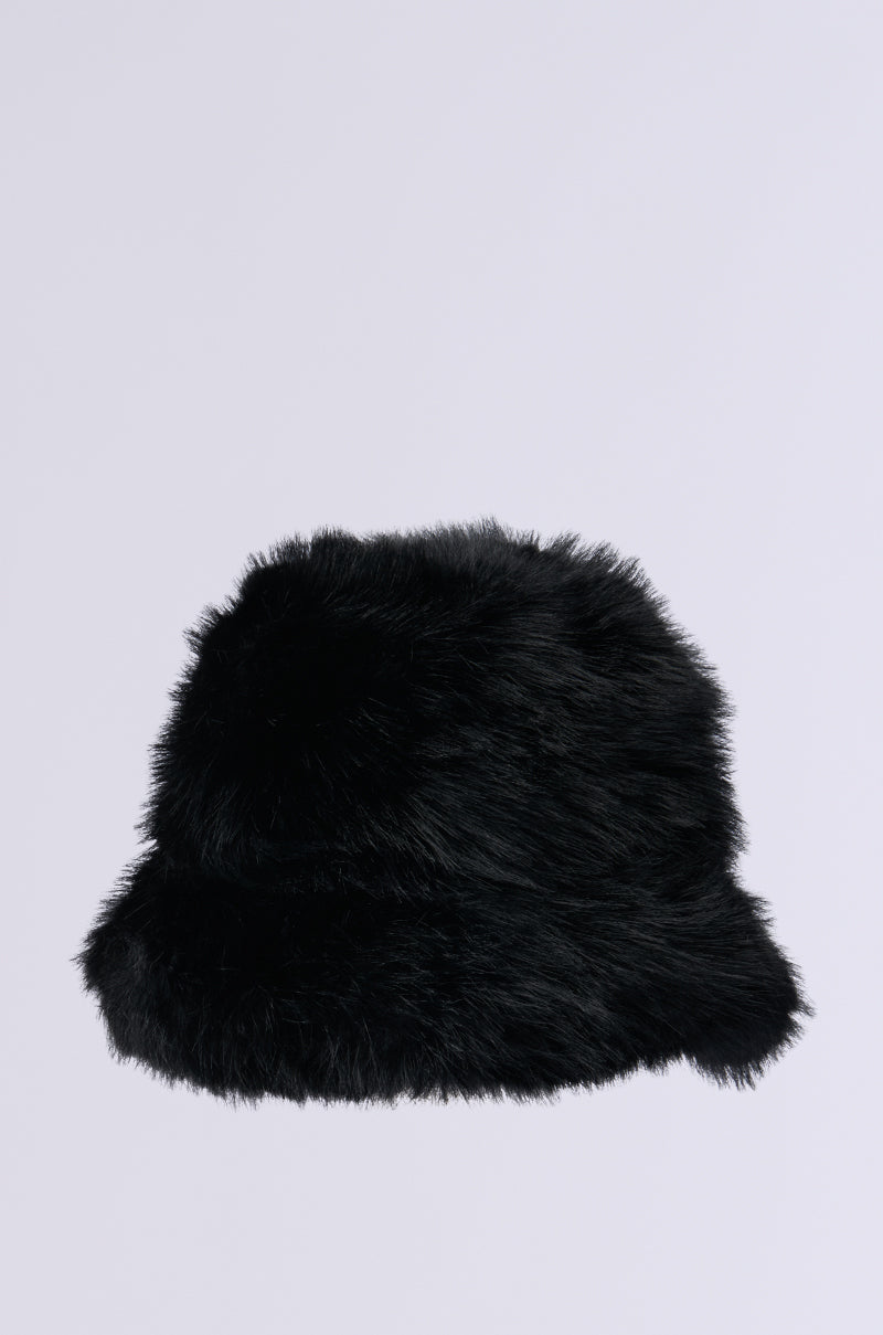 The APRES SKI FAUX FUR BUCKET HAT IN BLACK from the AKIRA Label, showcasing a plush and fluffy texture, is beautifully set against a simple light gray background. Ideal for cold weather outfits, this fashionable accessory seamlessly blends warmth with modern elegance.