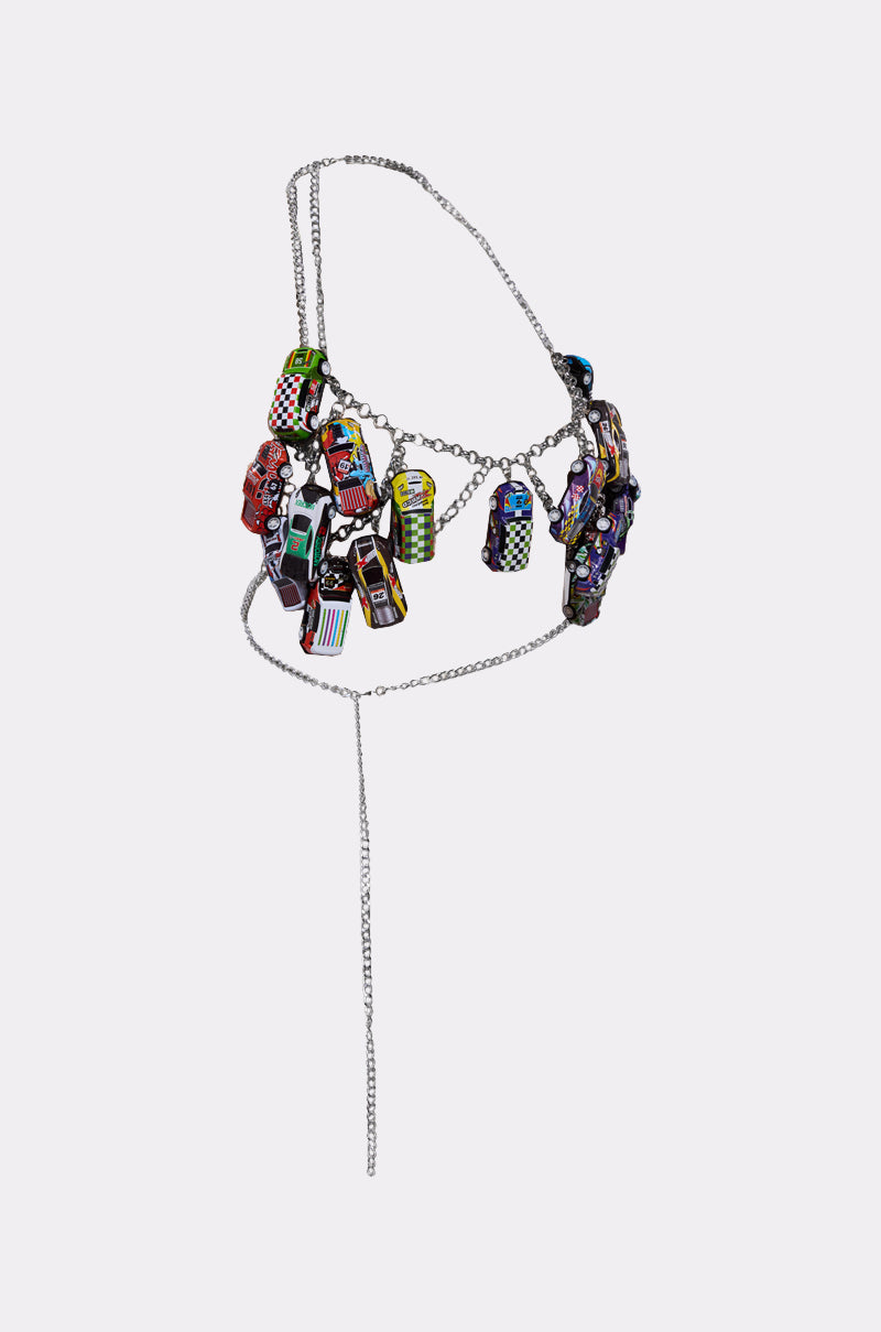 Make a statement with the I GO FAST RACE CAR BODY CHAIN, a metallic silver harness adorned with vibrant miniature car charms, each featuring detailed patterns and bright colors—all set against a plain white background.