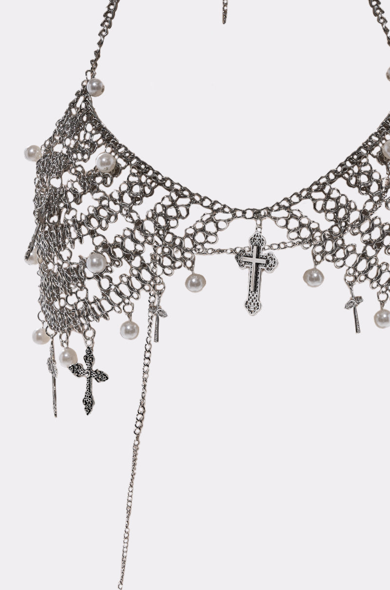 A close-up of the CHARMED LIFE BODY CHAIN, a silver layered necklace featuring intricate meshwork, small pearls, and cross-shaped pendants—a striking piece of gothic jewelry.