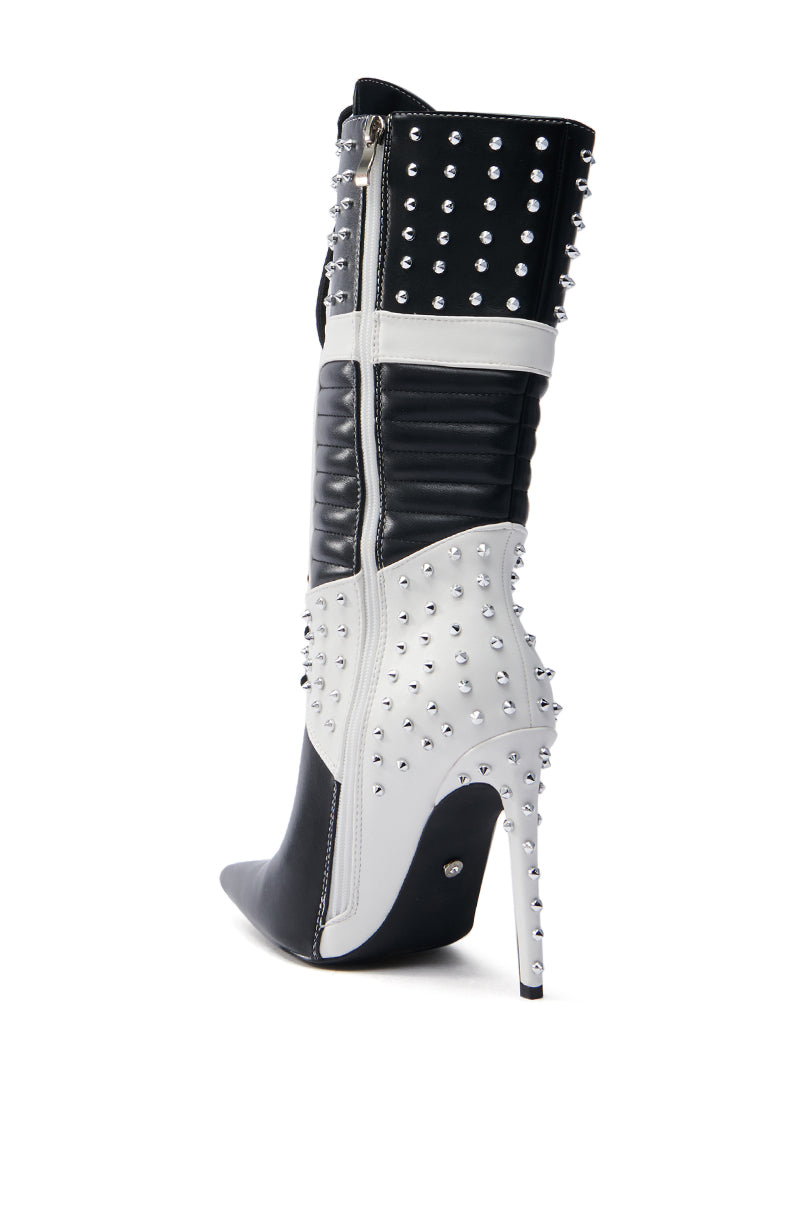 The AZALEA WANG OCTOBI BLACK AND WHITE STILETTO BOOT flaunts a faux leather upper with metallic studs, a pointed toe, and side zipper. Its stiletto heel and textured design offer bold, edgy style.