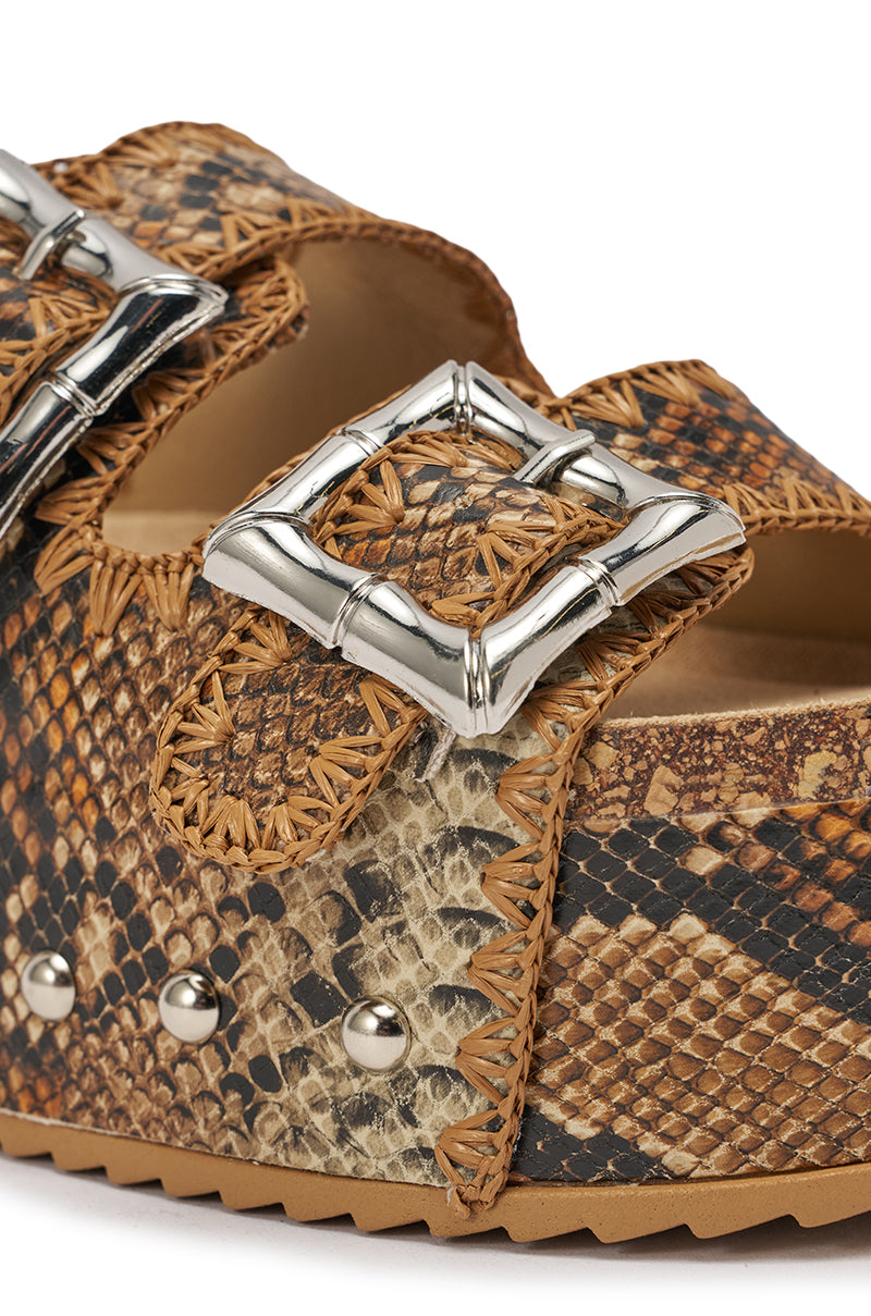 Close-up of the AZALEA WANG OHKAY SNAKE FLATFORM STUD EMBELLISHED SLIP ON SANDAL, featuring brown snake print faux leather, silver stud accents, a large square silver buckle, and tan woven stitching along the edges. 6