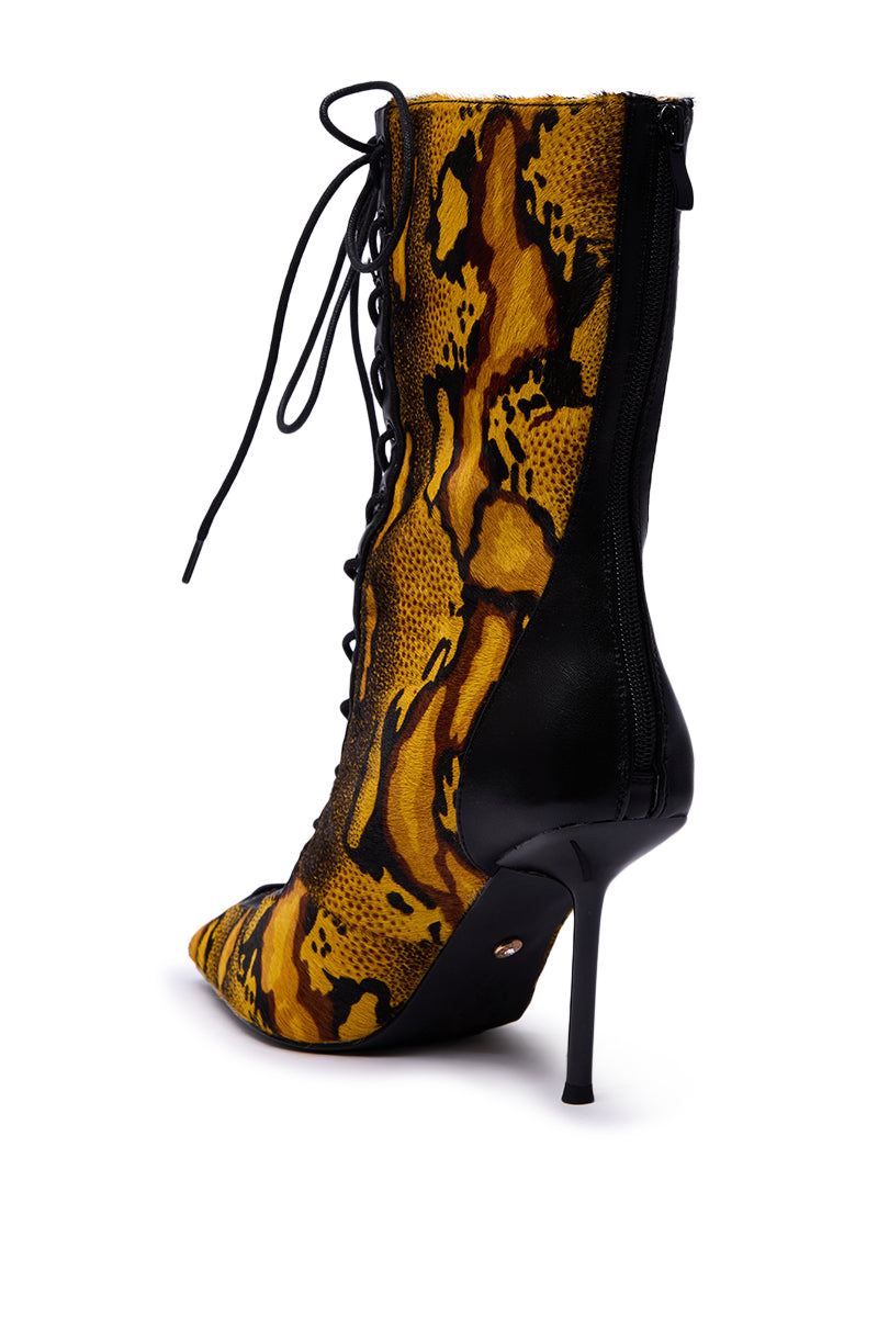 The AZALEA WANG OLIVERS YELLOW STILETTO LACE UP BOOTIE features a yellow and black snakeskin pattern with genuine pony hair, black leather accents, a pointed toe, lace-up front, and back zipper.