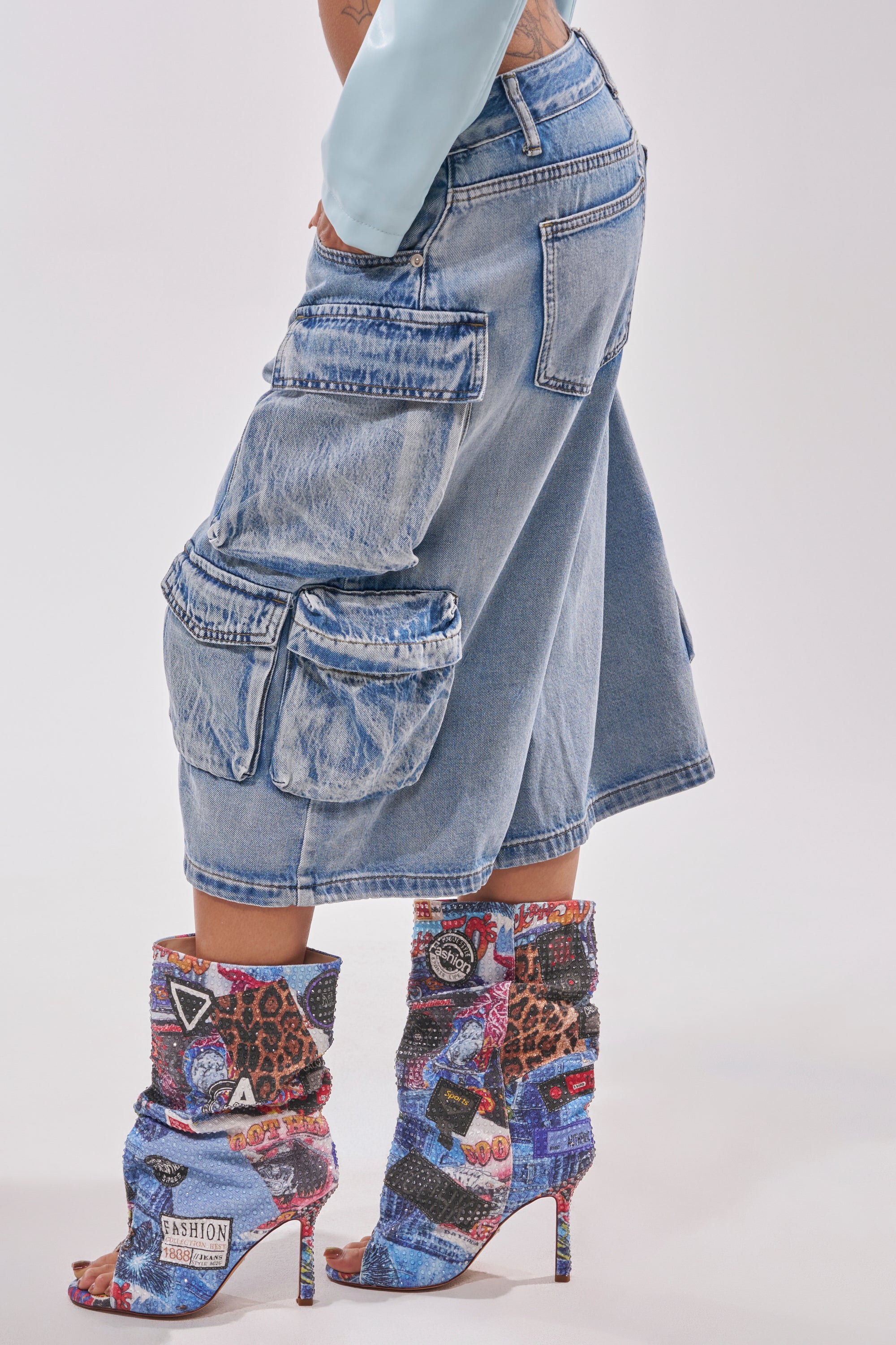 Wearing the TOO MUCH FUN CARGO BERMUDA SHORTS with large side pockets and patterned high-heeled boots, a person showcases vibrant festival style against a plain light background. 2