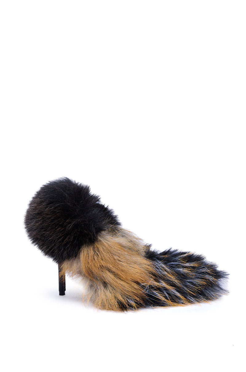 The AZALEA WANG OMIRCON Black and Tan Fur Stiletto Pump is a pointed-toe heel covered in multi-colored faux fur—mainly black, brown, and gray—giving it an animal-like look that contrasts strikingly against the white background.
