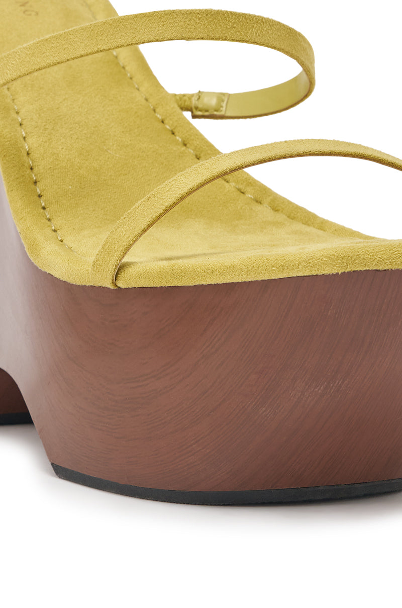 Close-up of the AZALEA WANG ONNI CITRON WEDGE SANDAL, featuring yellow suede, thin straps, and a chunky, brown wood-textured platform sole, shown from an angle highlighting the front and side. 7