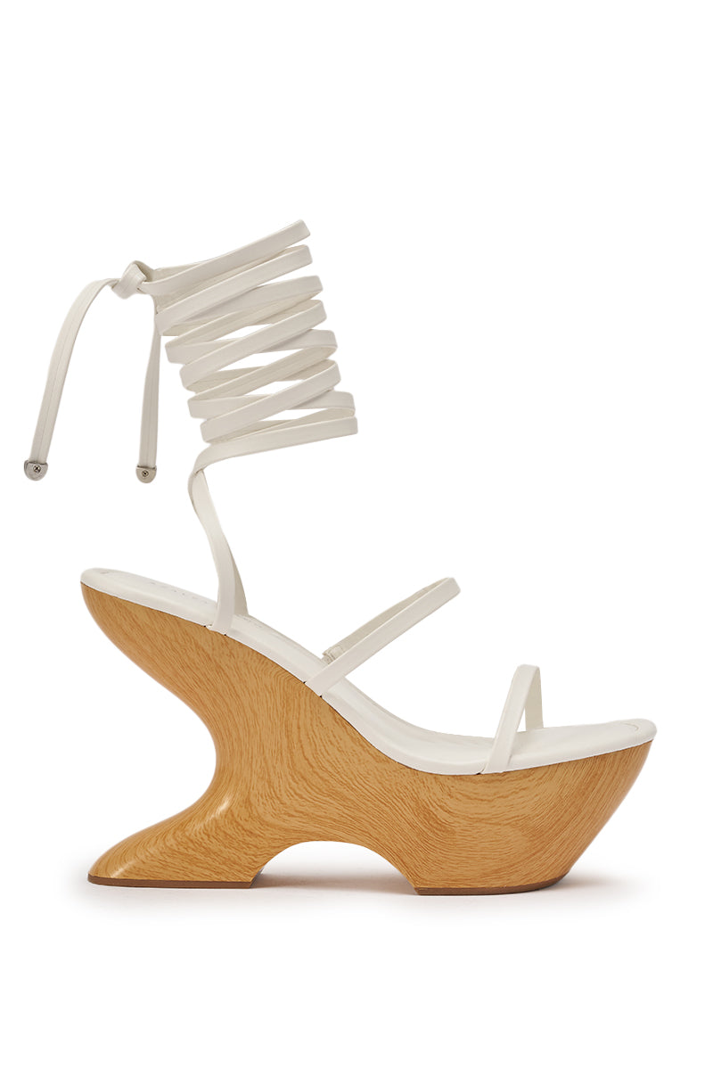 The AZALEA WANG ONNI White Strappy Upper Wood Wedge is a white sculptural sandal with a faux leather upper, wooden platform heel, and lace-up ankle tie, shown from the side. 6