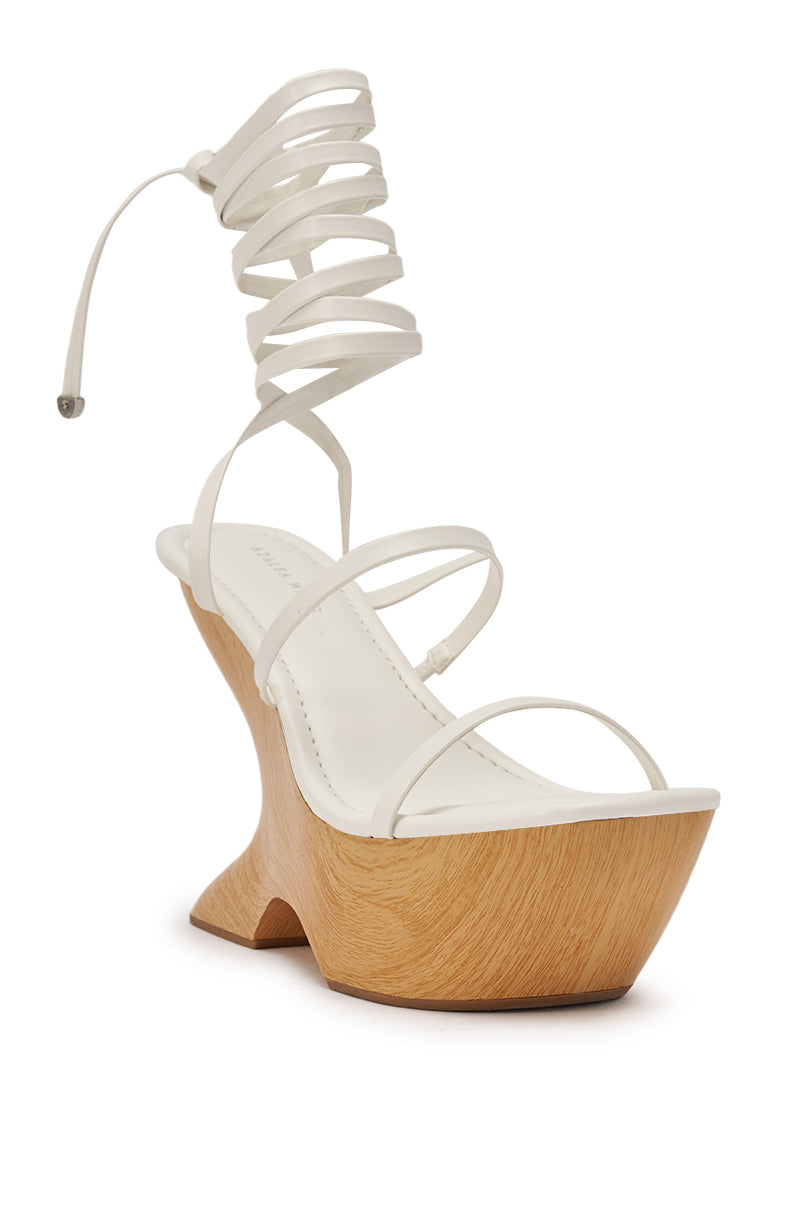 The AZALEA WANG ONNI WHITE STRAPPY UPPER WOOD WEDGE is a white sculptural sandal with a faux leather strappy upper, unique wooden wedge sole, and an elegant lace-up ankle tie that wraps stylishly upward. 7