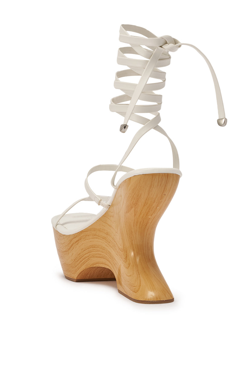 The AZALEA WANG ONNI WHITE STRAPPY UPPER WOOD WEDGE features a white faux leather upper, wrap-around lace-up ankle ties, and a sculpted wooden heel, shown from the rear against a white background. 8