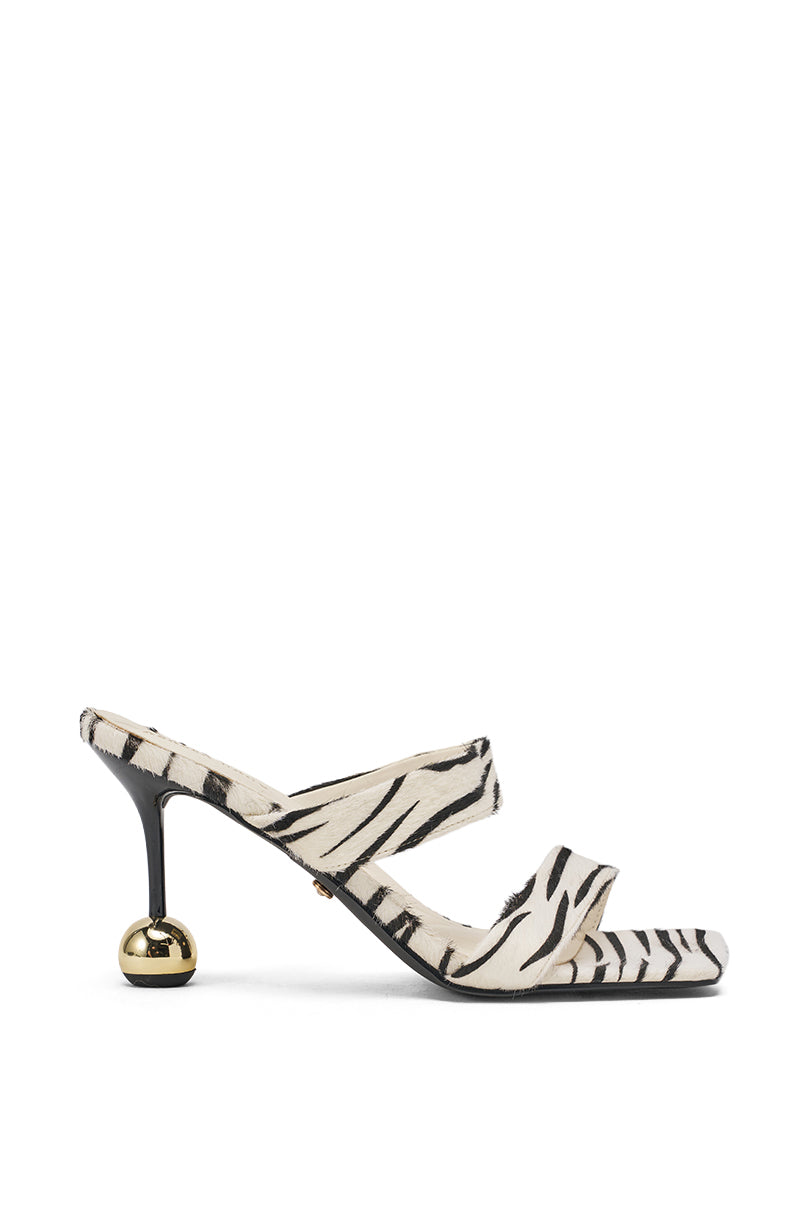 The AZALEA WANG OPHIEL ZEBRA PONY HAIR SANDAL features a zebra-print calf hair design, two straps, and a distinctive gold sphere heel, displayed on a plain white background. 3