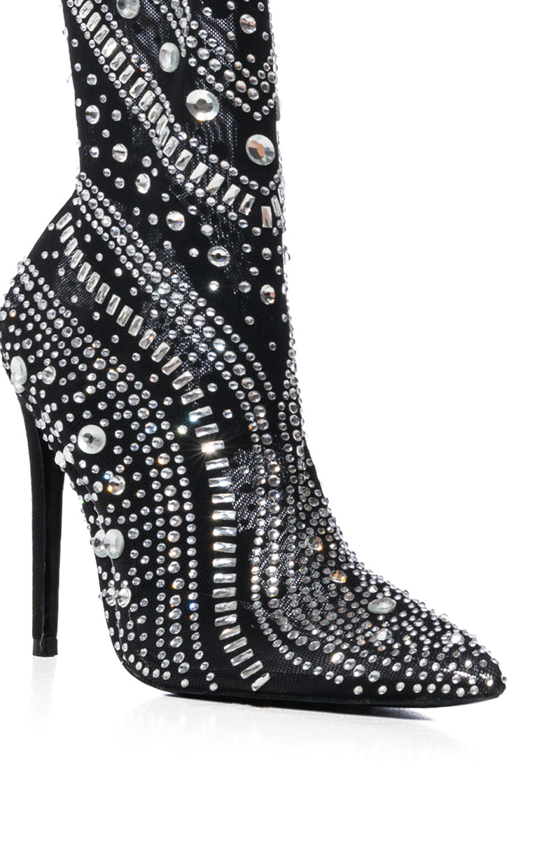 The AZALEA WANG OPRY BLACK EMBELLISHED MESH BOOTIE features a close-up view of intricate patterns with silver and clear rhinestones, covering the visible section and beautifully perched on a sleek stiletto heel. 7