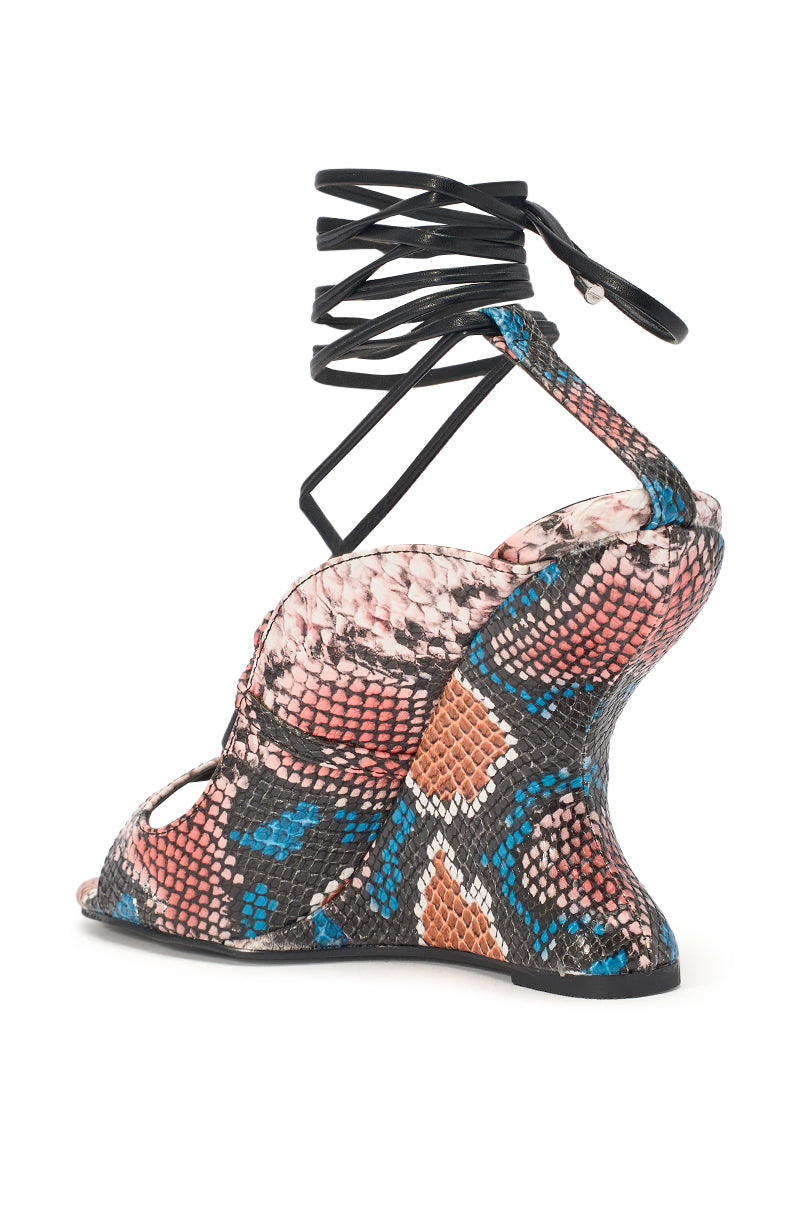 The AZALEA WANG ORENA SNAKE MULTI WEDGE LACE UP SANDAL is a high-heeled faux leather sandal with a sculpted wedge heel, vibrant black, pink, orange, and blue snake print, and sleek lace-up ankle straps. 5