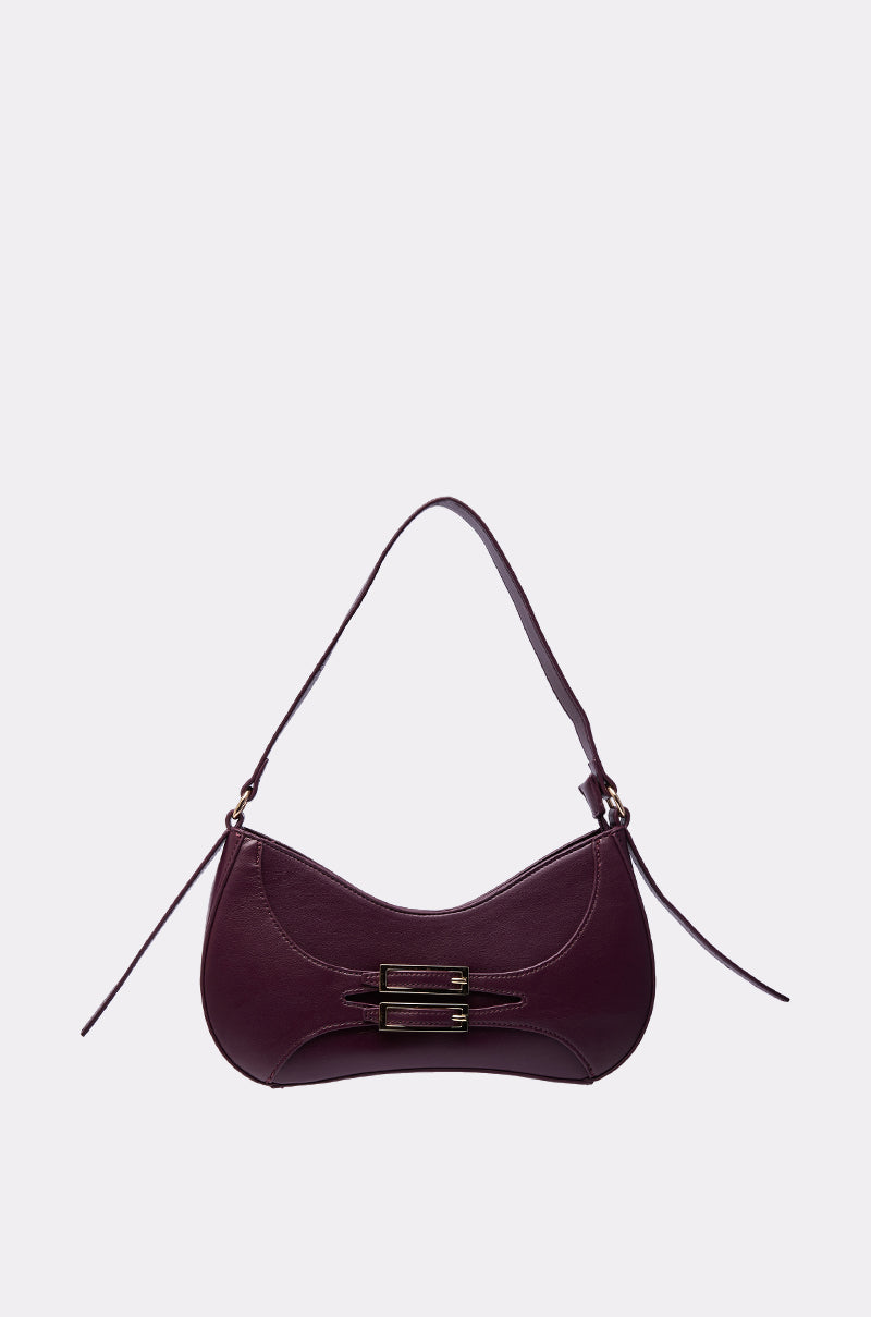 The PLUM PURSE is a dark purple faux leather shoulder bag featuring a curved baguette silhouette, single strap, and gold-tone front buckle, shown on a plain light gray background. 0