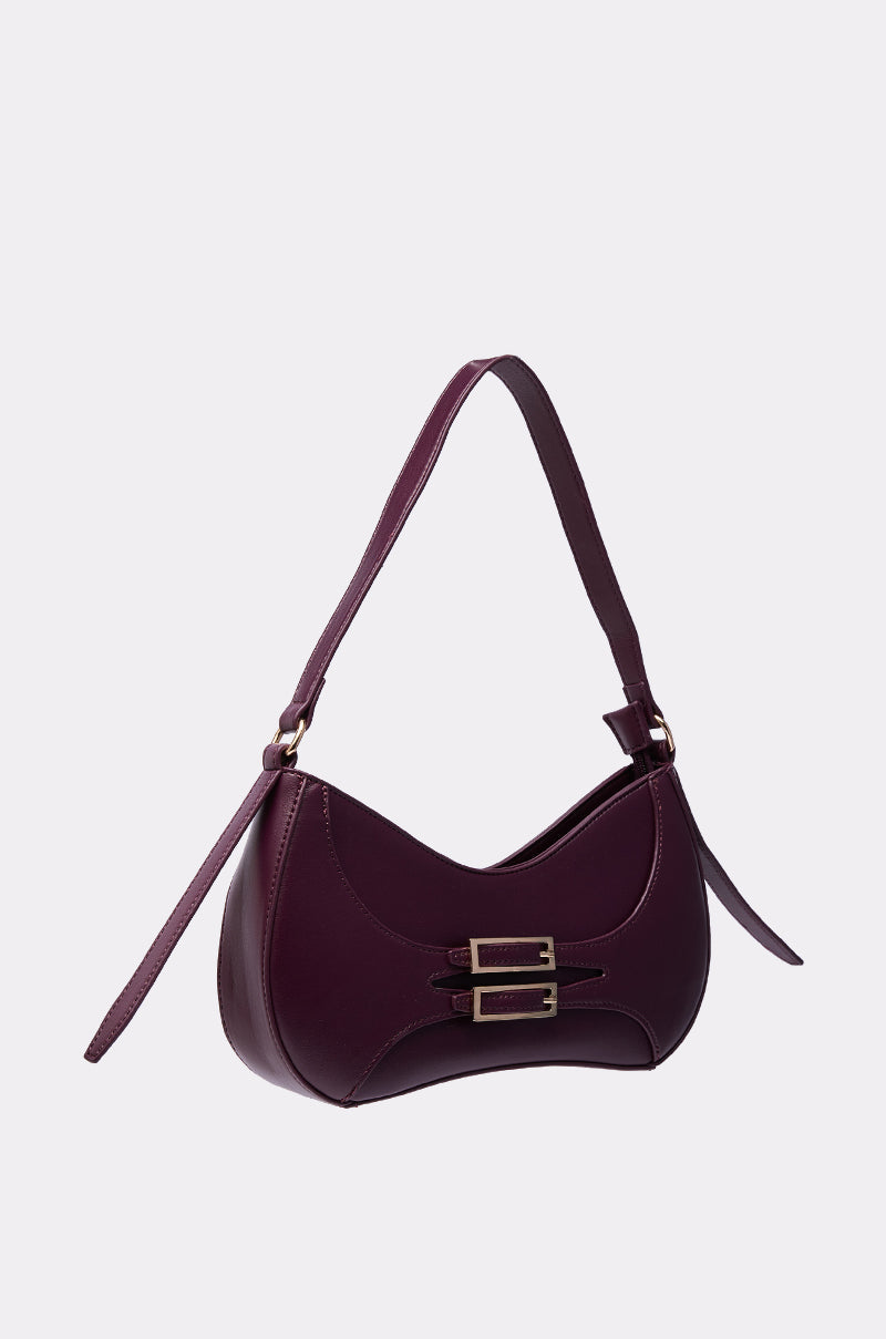 The PLUM PURSE is a maroon faux leather shoulder bag with a curved design, single strap, gold-tone hardware, and double front buckles, shown against a plain white background. 2