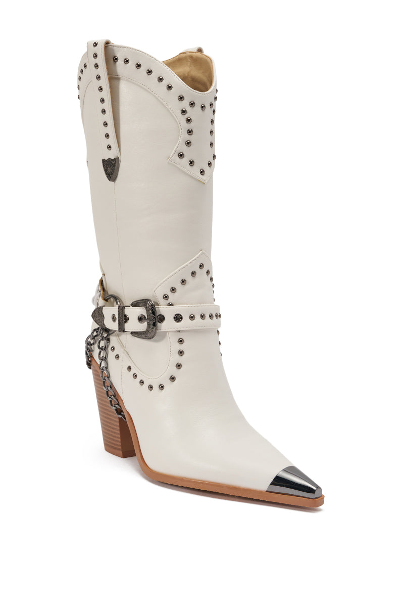 The AZALEA WANG OSBORN WHITE WESTERN BOOTIE features white faux leather, silver studs, a decorative harness and chain, a pointed toe with black cap, and a stacked tan heel—making it a bold mid-calf western boot statement.