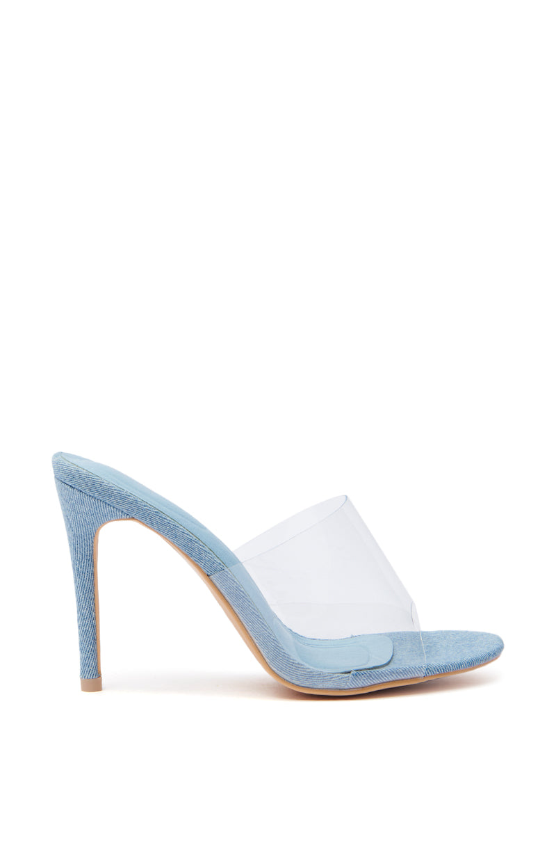The AKIRA OSWEGO DENIM NEW SLIP ON MULE SANDAL is a chic light blue denim stiletto featuring a clear front strap, pointed toe, and comfort cushion insole. It blends modern design with outstanding comfort effortlessly.