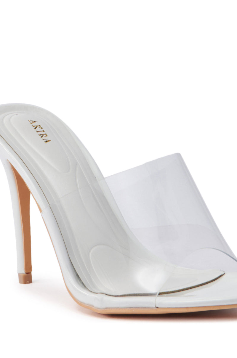 The AKIRA OSWEGO WHITE SLIP ON SANDAL features a high stiletto heel with a translucent PVC vamp and light-colored sole. Its open toe design and slender heel enhance its elegance, making it a sophisticated choice for any occasion.