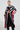 The individual is dressed in the COME AND GET LONG CARDIGAN, featuring a striking zebra colorblock design in black, white, and red. Made from a comfortable knit fabric, the cardigan includes convenient pockets where their hands rest. This stylish piece is paired with high-waisted black jeans and knee-high boots, while their hair is elegantly styled in a sleek updo.