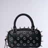 Introducing the SPIKED OUT EMBELLISHED PURSE: a stylish black purse adorned with silver spikes and circular grommets. This minimalist design features a convenient handle and is crafted from faux leather, making it an ideal accessory for a punk-inspired look. The bag is beautifully showcased against a plain gray background.