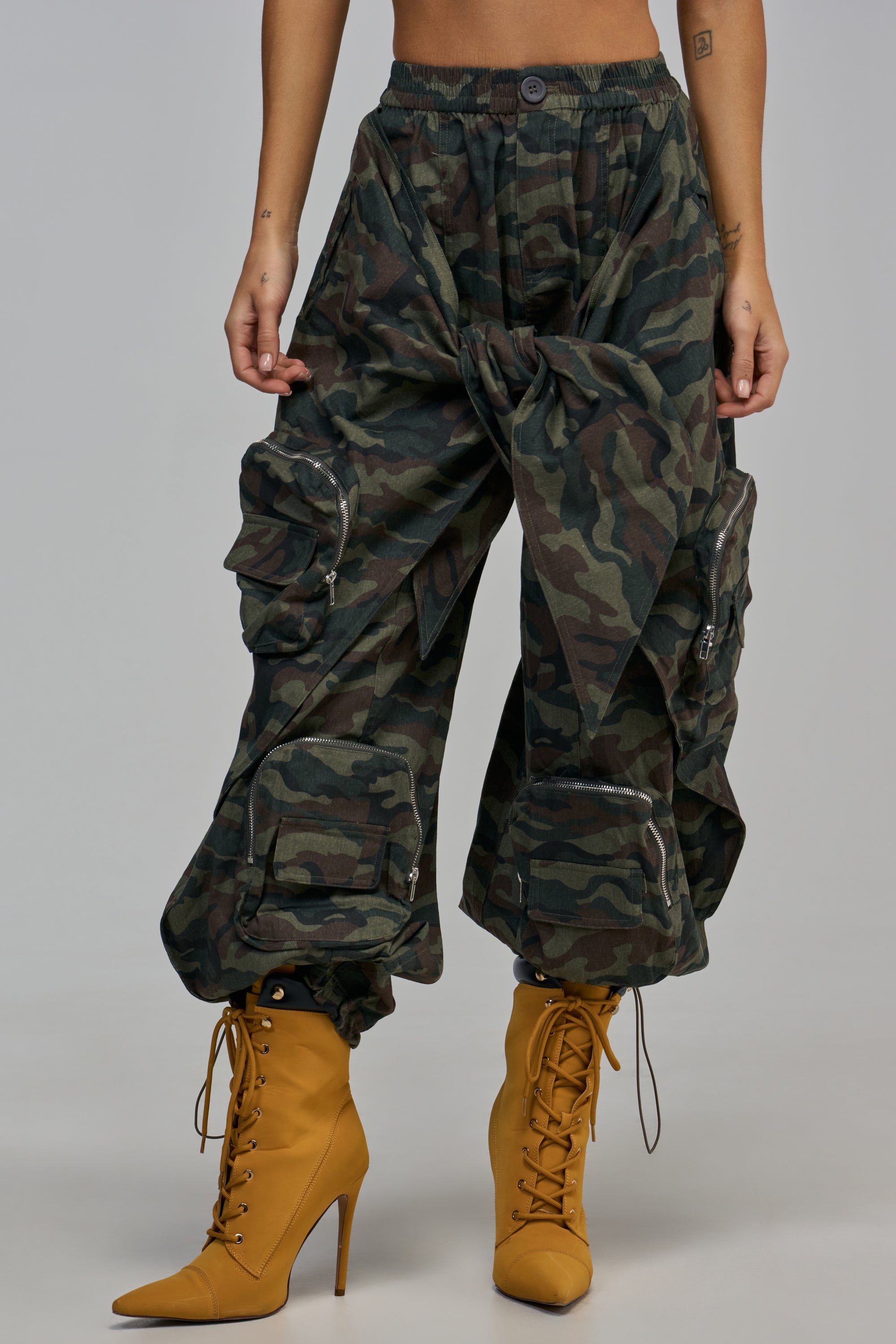 DO THE MOST TIE FRONT FRONT PANT IN CAMO, featuring a tied front detail and zippered pockets, styled with mustard yellow lace-up stiletto boots.