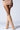 A person wearing a ribbed beige mini skirt and the AZALEA WANG PAITYN Fuzzy Boot in Brown, featuring a knee-high shaft, stands against a plain background. The focus is on the lower half, emphasizing the outfit's textures and the fluffy appearance of the boots.