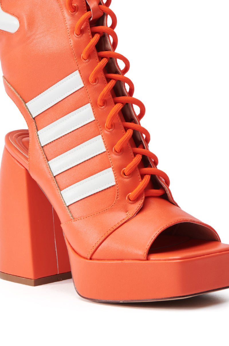 The AZALEA WANG PAMINA ORANGE CHUNKY SANDAL is a bright orange high-heeled shoe with a chunky platform sole and open toes, made of faux leather. It features white stripes, lace-up details, and a robust block heel that enhances its bold and stylish design.