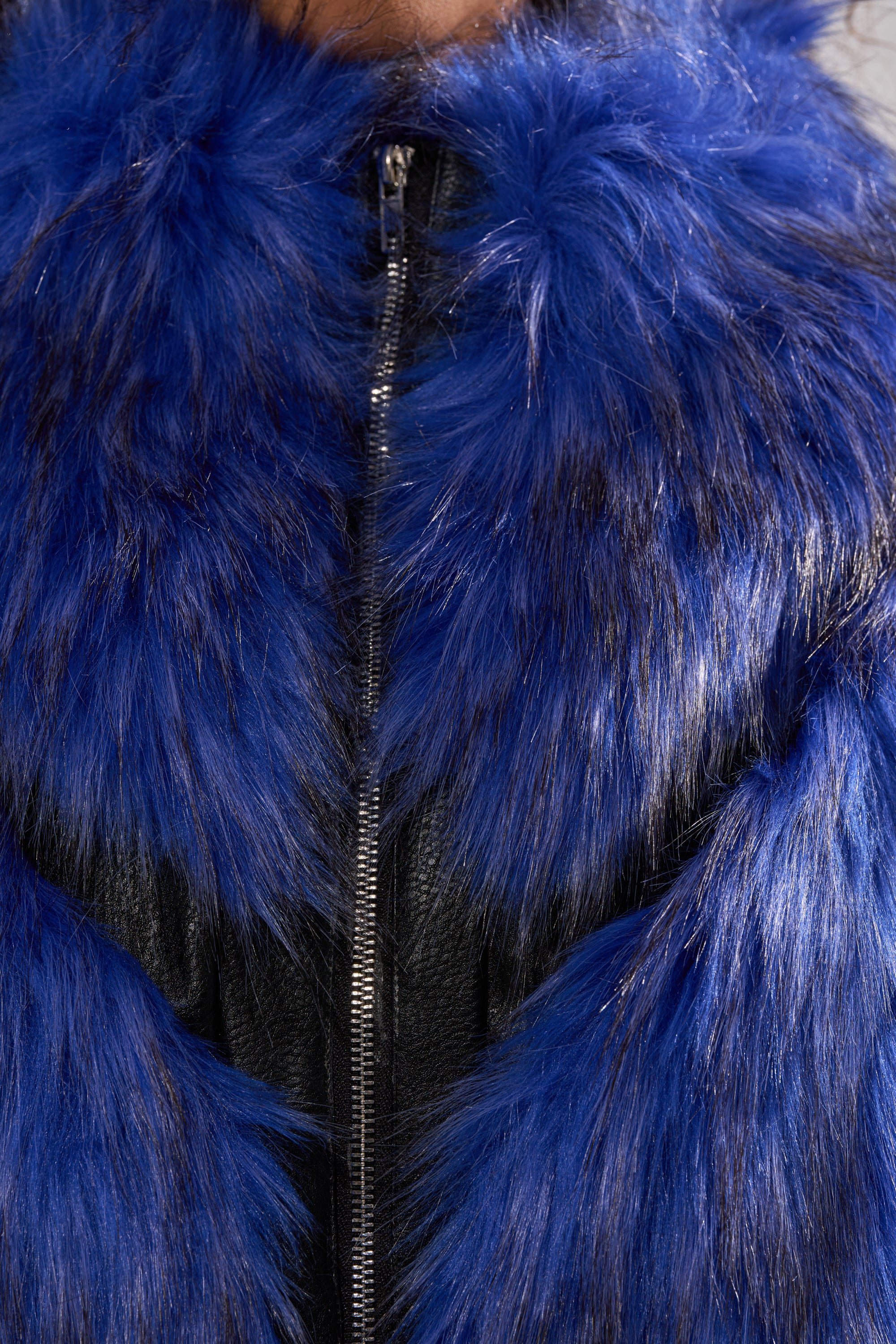 Close-up of a person wearing the ASTRO FUR PANEL MOTO jacket in electric blue faux fur with black trim and a visible center zipper. The soft, fluffy texture gives this piece bold standout style. 9