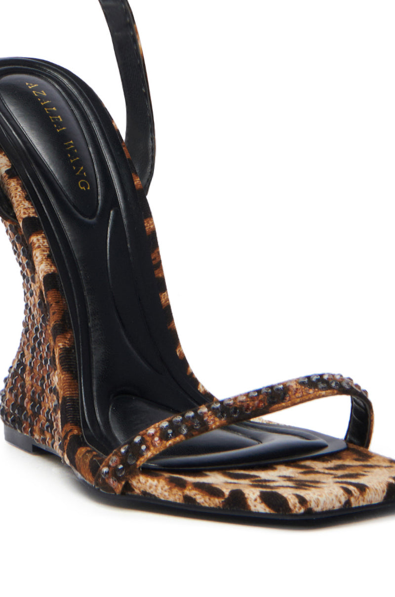 The AZALEA WANG PANTHERESS LEOPARD WEDGE SANDAL features a distinctive curved heel, brown and black leopard print with rhinestone strap and heel embellishments, a black branded insole, and an elegant suede textile upper.
