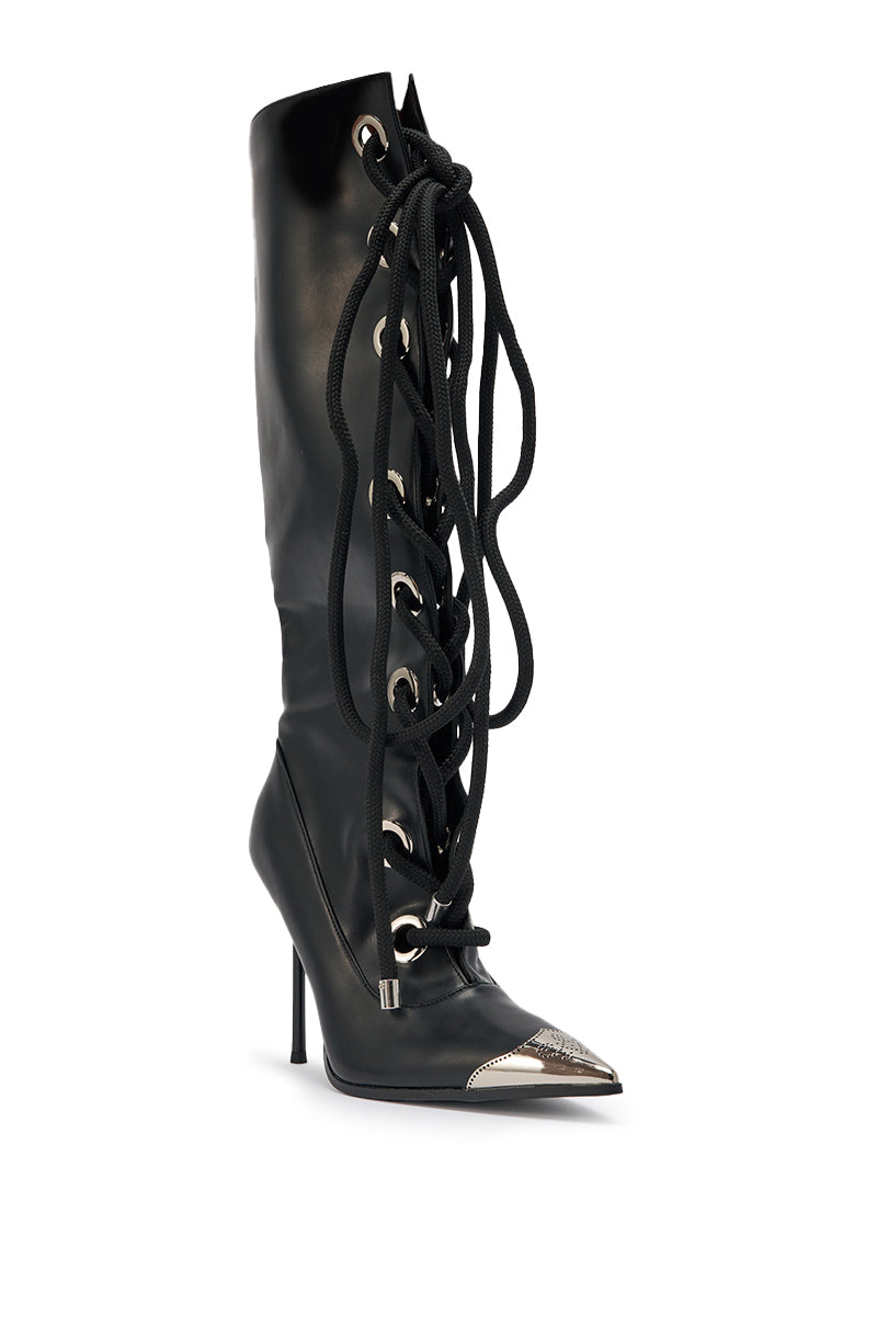 The AKIRA GOLD PANTOUM BLACK PU HARDWARE BOOT is a knee-high black faux leather boot with oversized front laces, large metal eyelets, a pointed toe, and a metallic silver toe cap. 6