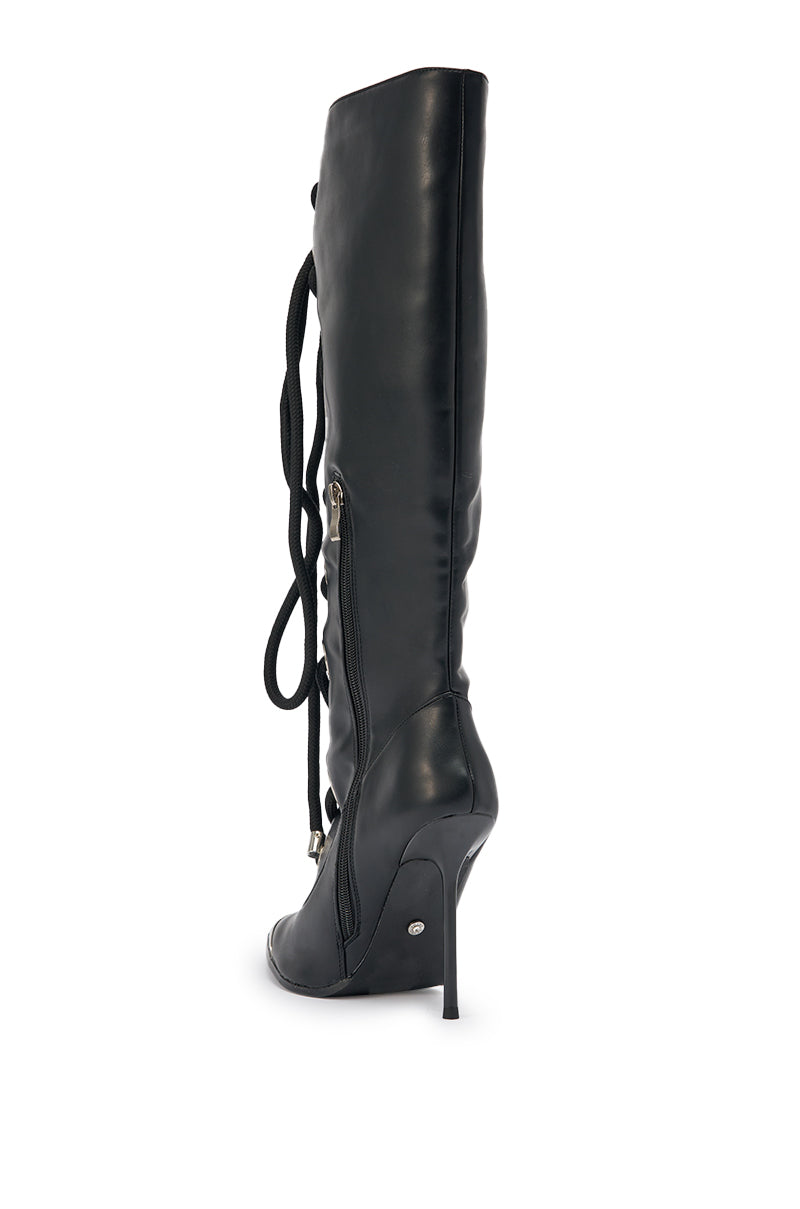 The AKIRA GOLD PANTOUM BLACK PU HARDWARE BOOT is a knee-high, black faux leather stiletto with side zipper and front lace-up details, shown in profile on a white background. 7