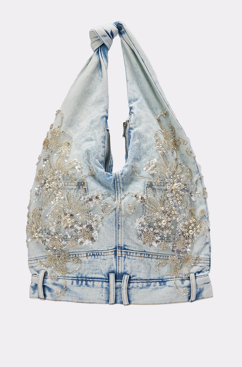The BLESSING IN DENIM EMBELLISHED SHOULDER BAG features light blue denim, a knotted handle, silver sequin and bead floral details, and decorative seams for a striking AKIRA Label look. 2