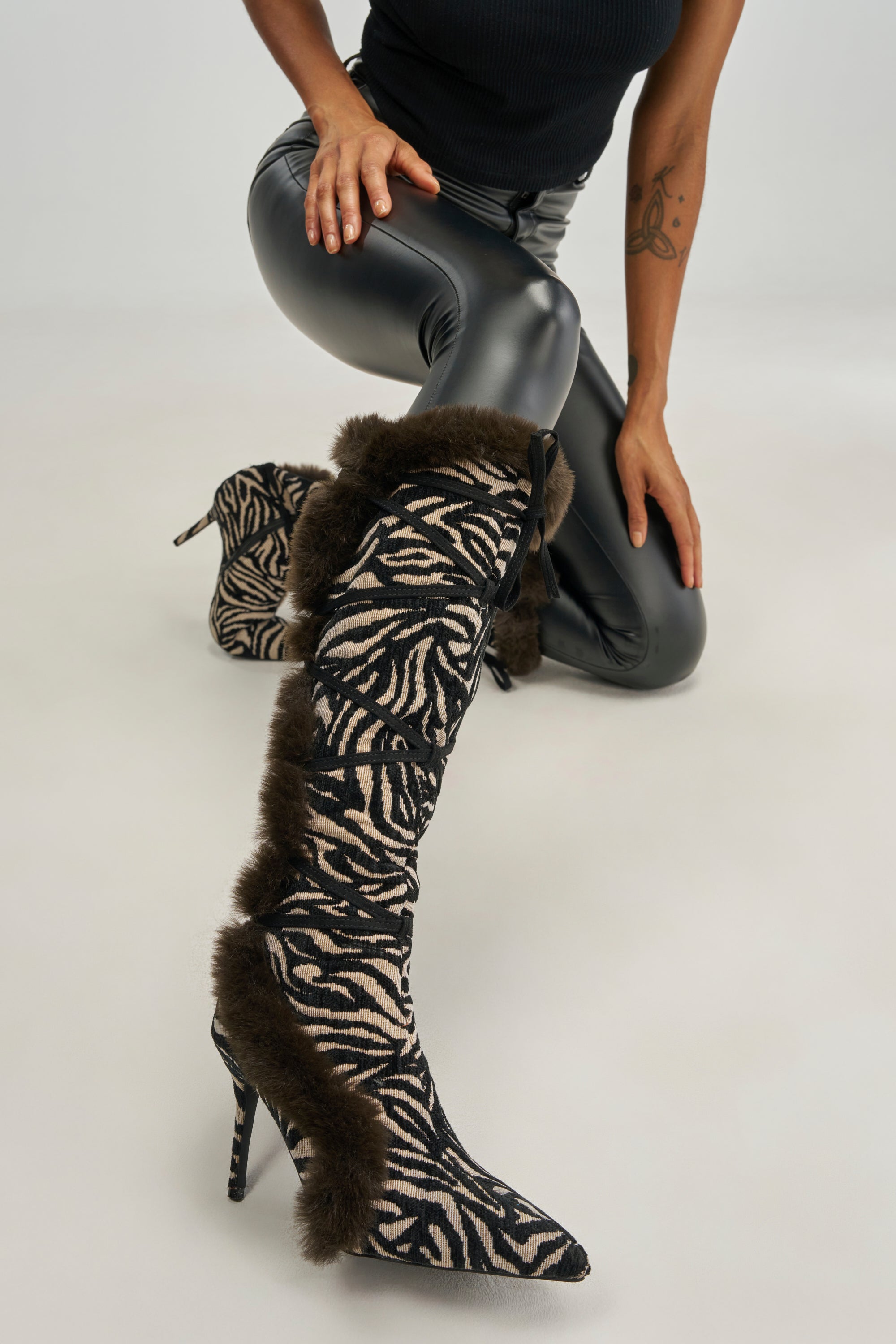 AZALEA WANG PAOLA ZEBRA FUR STILETTO BOOT knee-high zebra print boots with a lace-up front and faux fur trim.