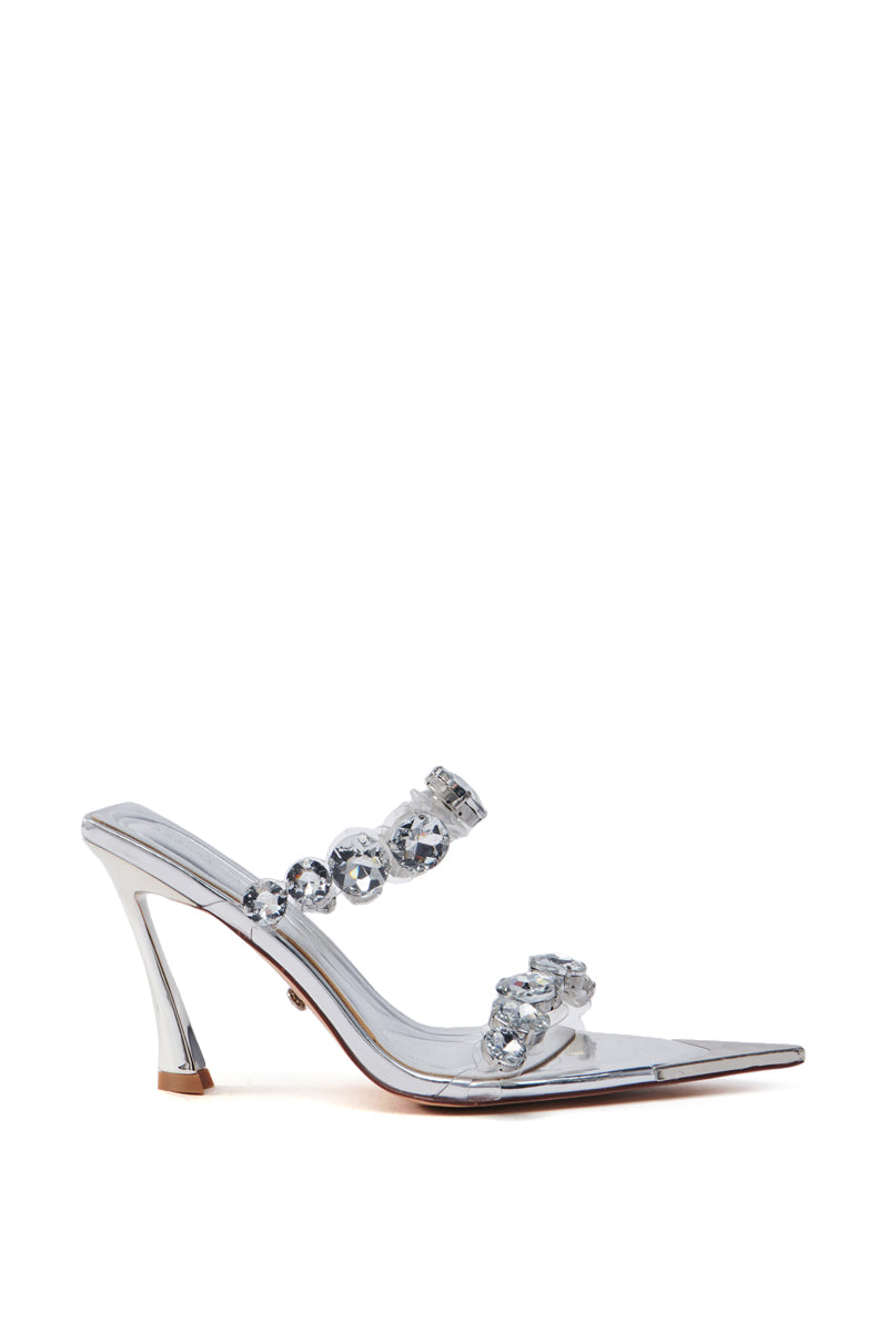 The AZALEA WANG PAOLINA Silver Rhinestone Chunky Heel Sandal features a stylish transparent design with a pointed toe, two straps decorated with large clear gemstones, metallic faux leather construction in glossy silver, and sleek stiletto heels.